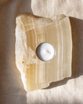 Tealight candle holder made of onyx stone on a beige fabric background