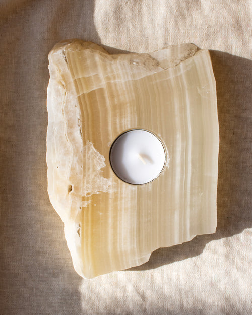 Tealight candle holder made of onyx stone on a beige fabric background