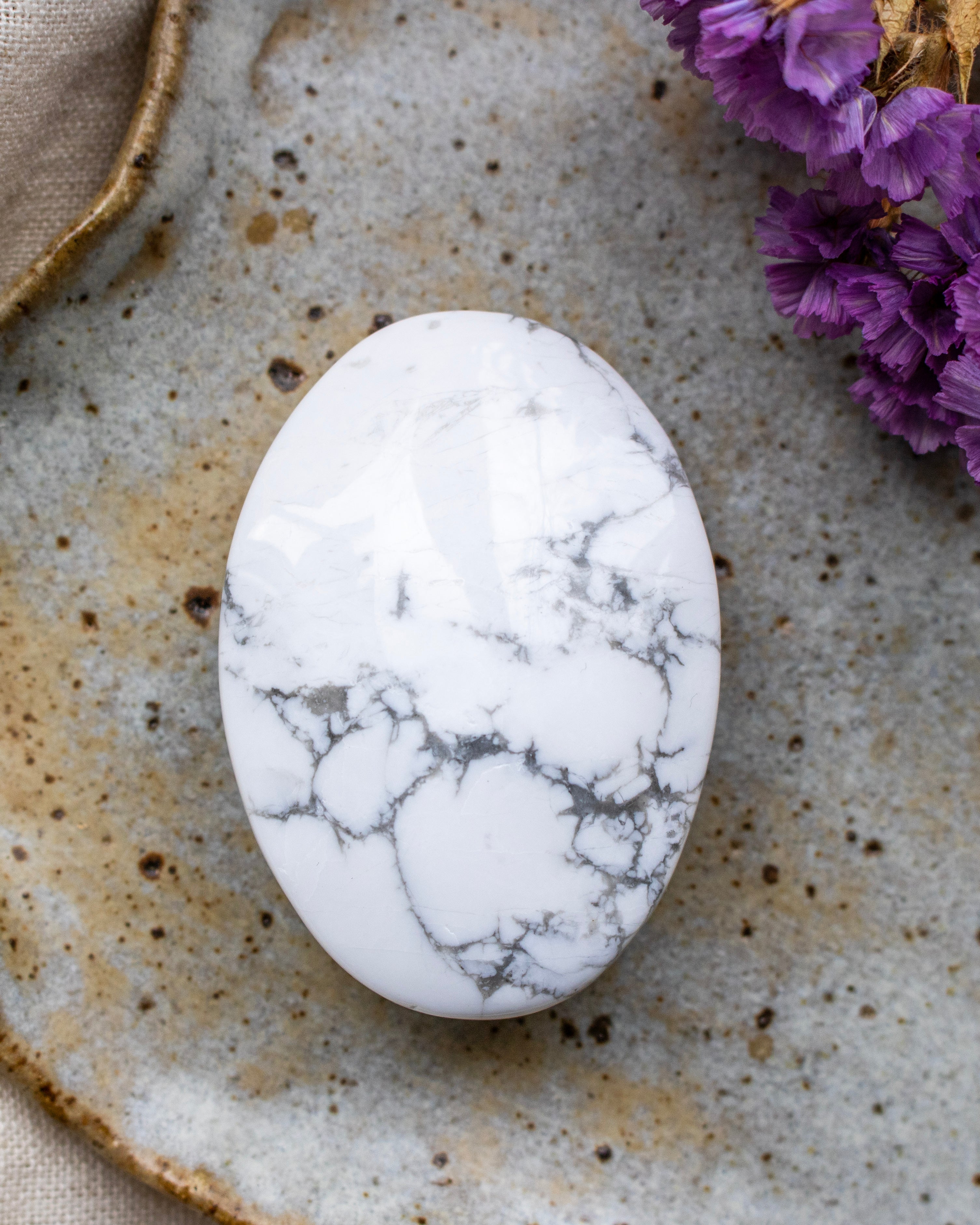 White marbled stone on a textured surface with purple flowers