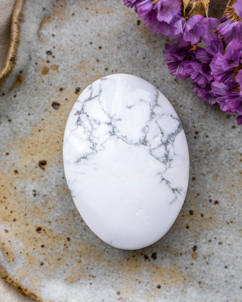 White marbled stone on a textured surface with purple flowers