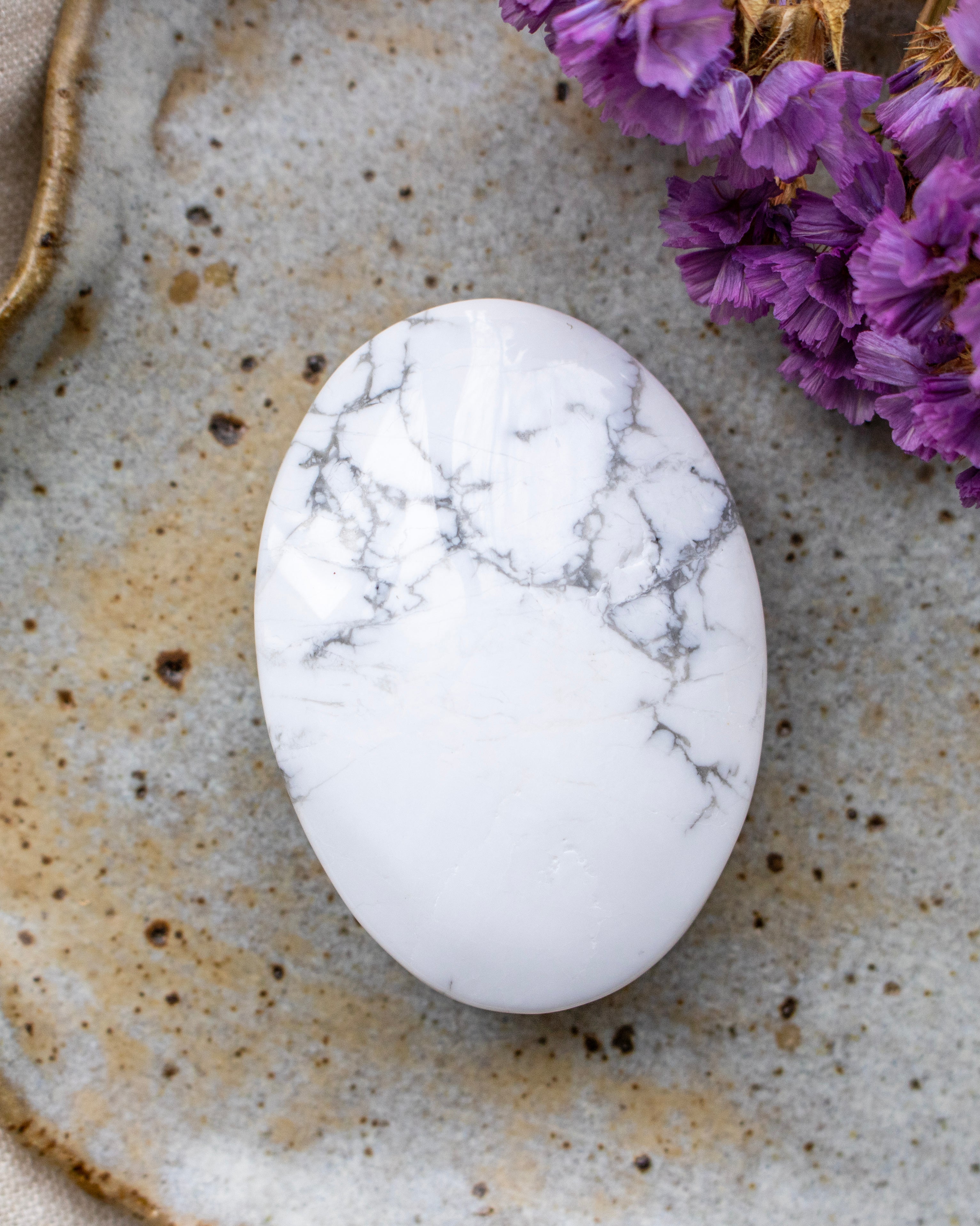White marbled stone on a textured surface with purple flowers