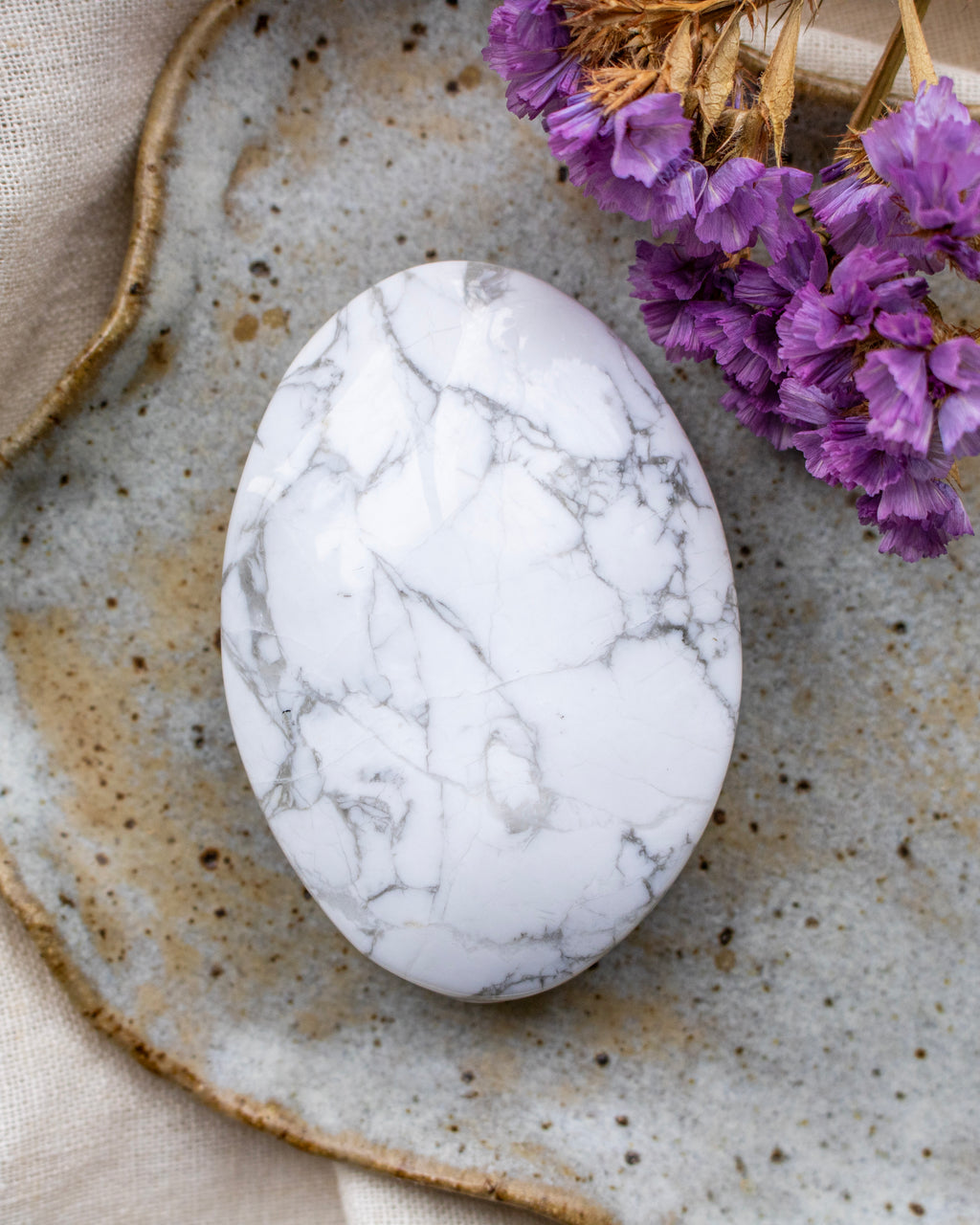 Marble-patterned stone on a textured ceramic plate with purple flowers