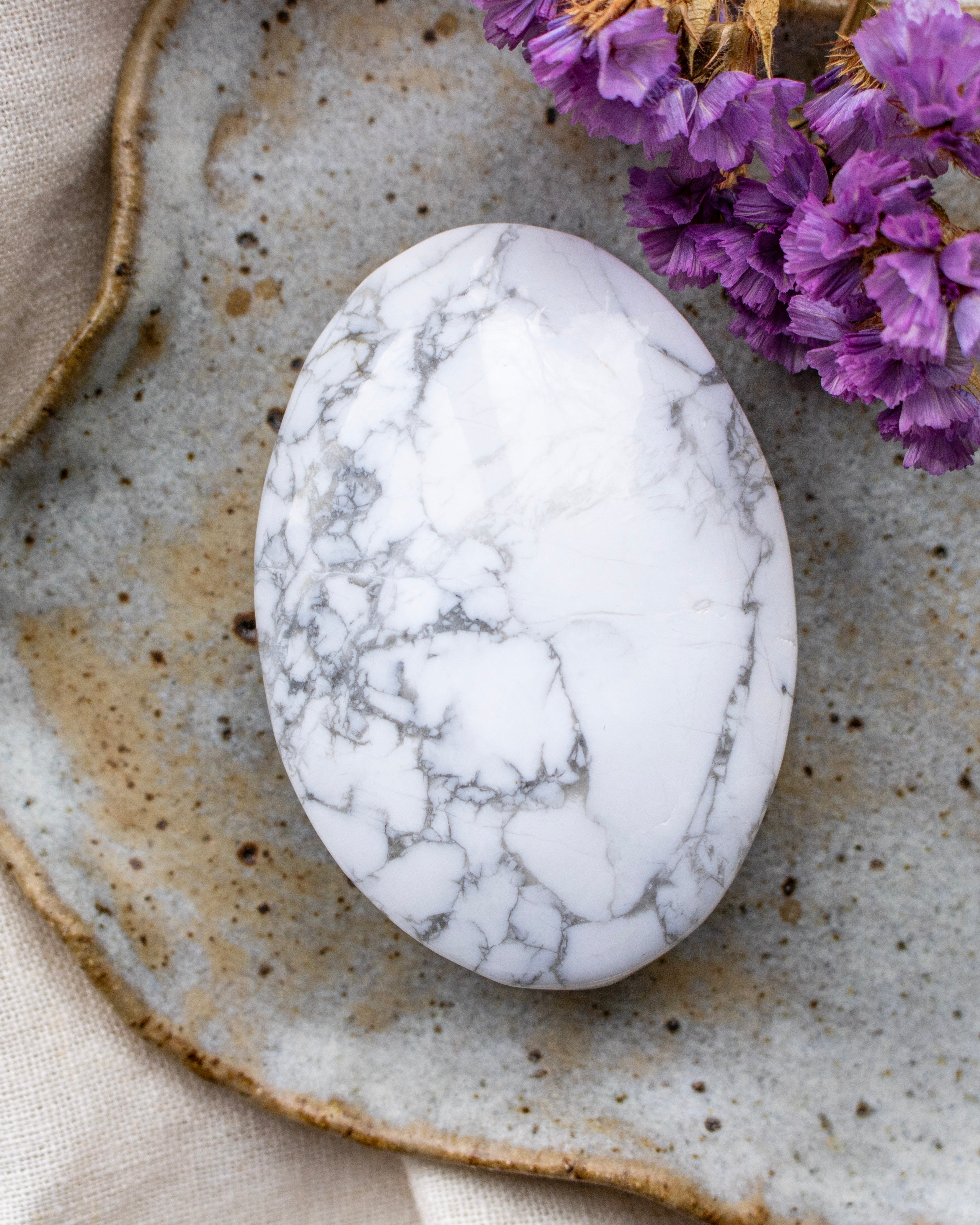 Marble-patterned stone on a textured surface with purple flowers