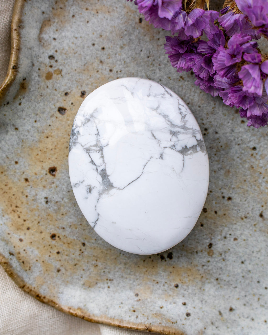 Marble-patterned stone on a textured ceramic plate with purple flowers