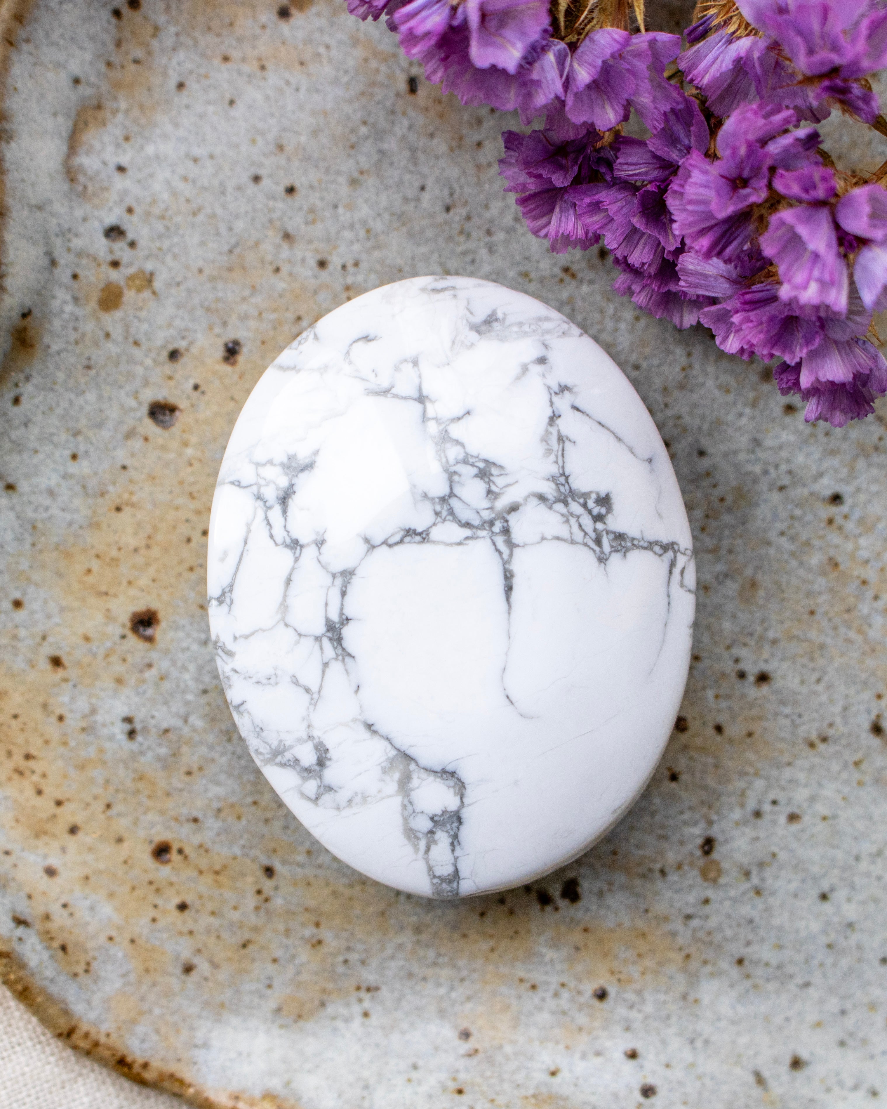 Marble-patterned stone on a textured surface with purple flowers