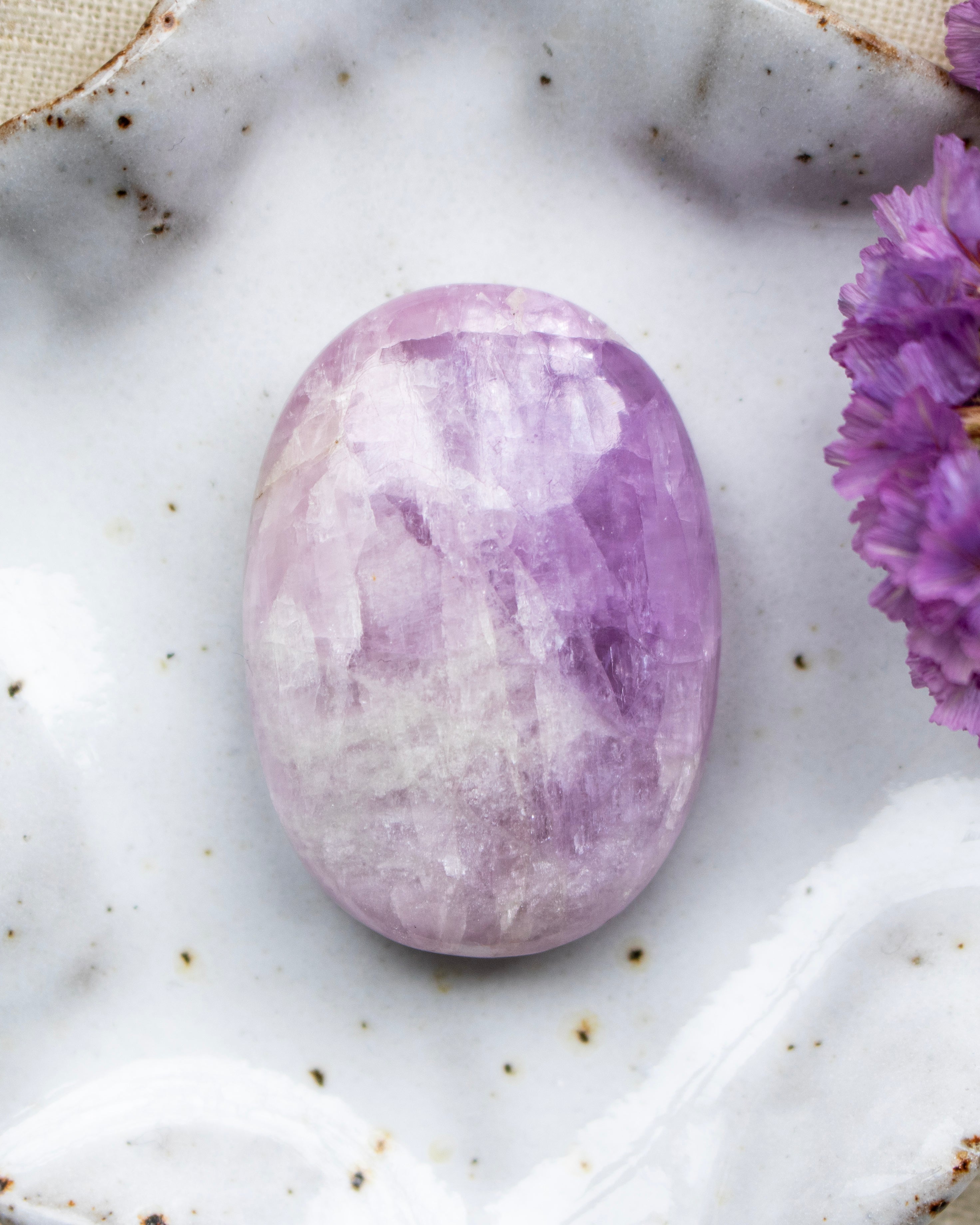 Purple crystal stone on a marble surface with purple flowers