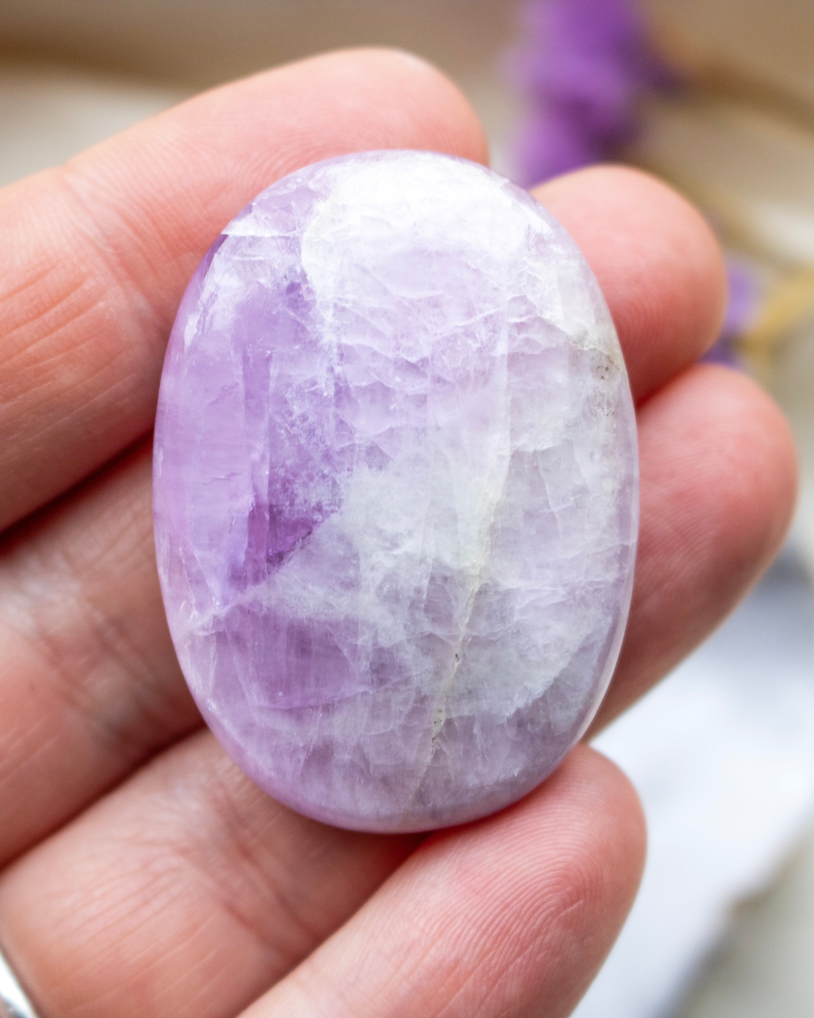 Purple and white stone held in a hand with a blurred background
