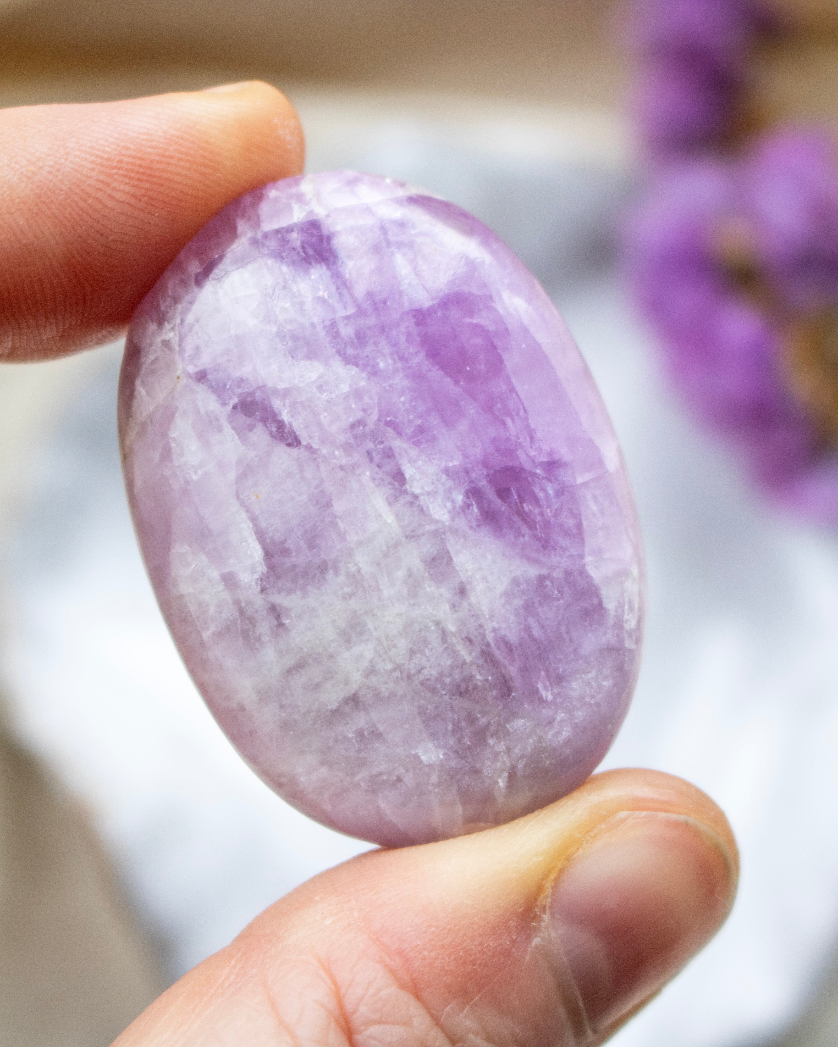 Hand holding a purple and white stone with a blurred background