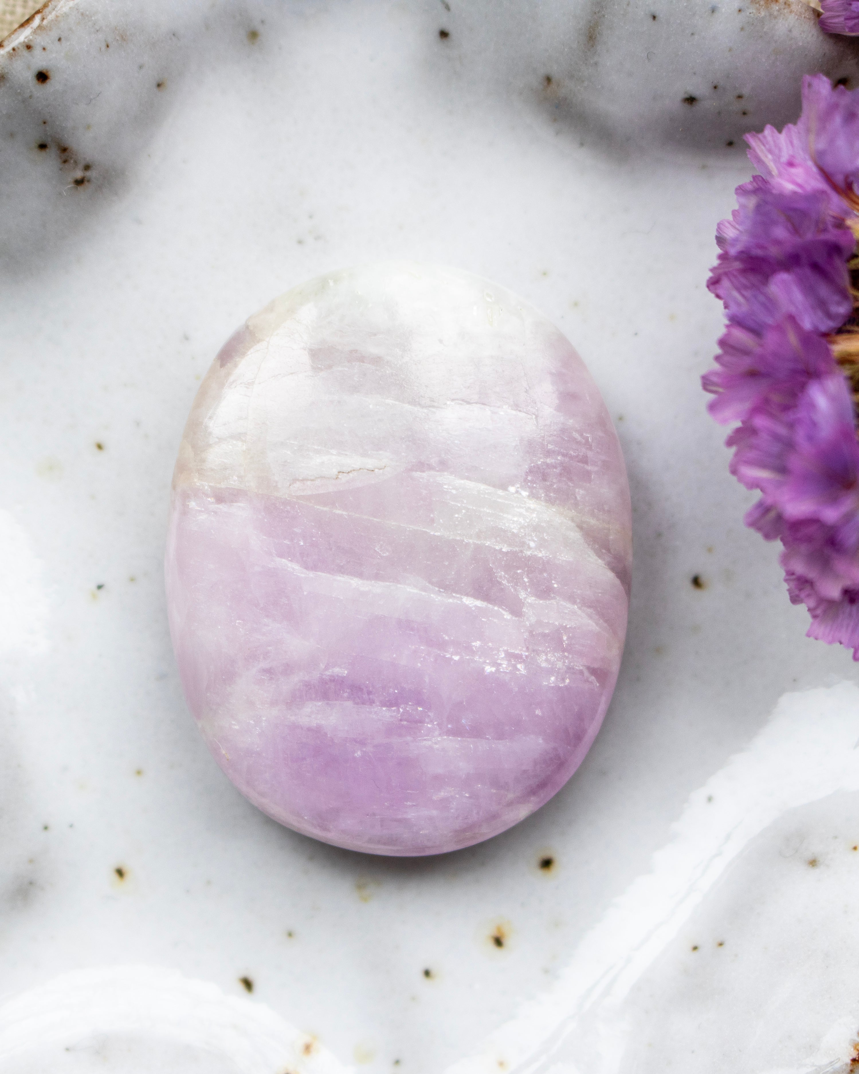 Purple stone on a white surface with a purple flower