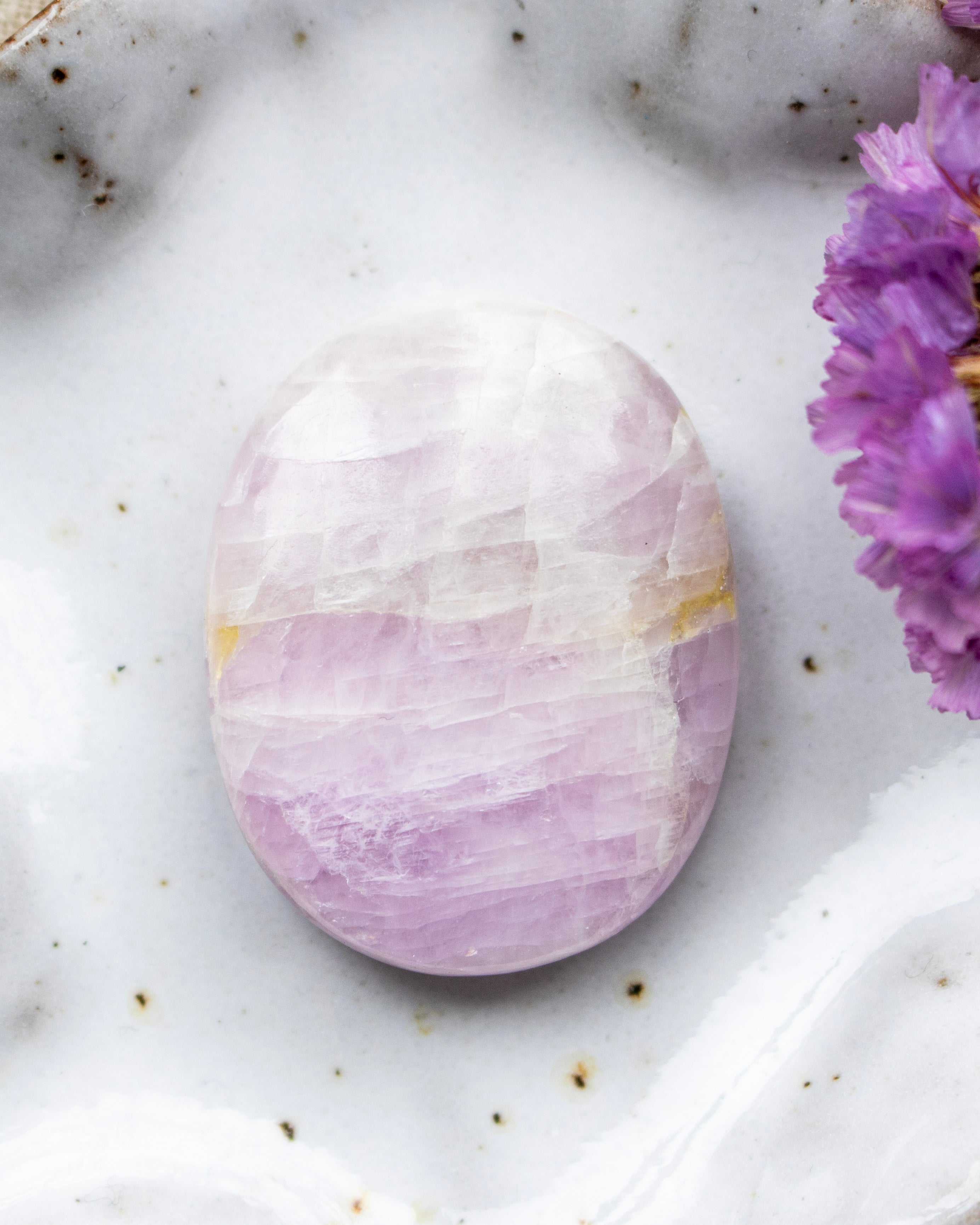 Purple and white stone on a marble surface with purple flowers