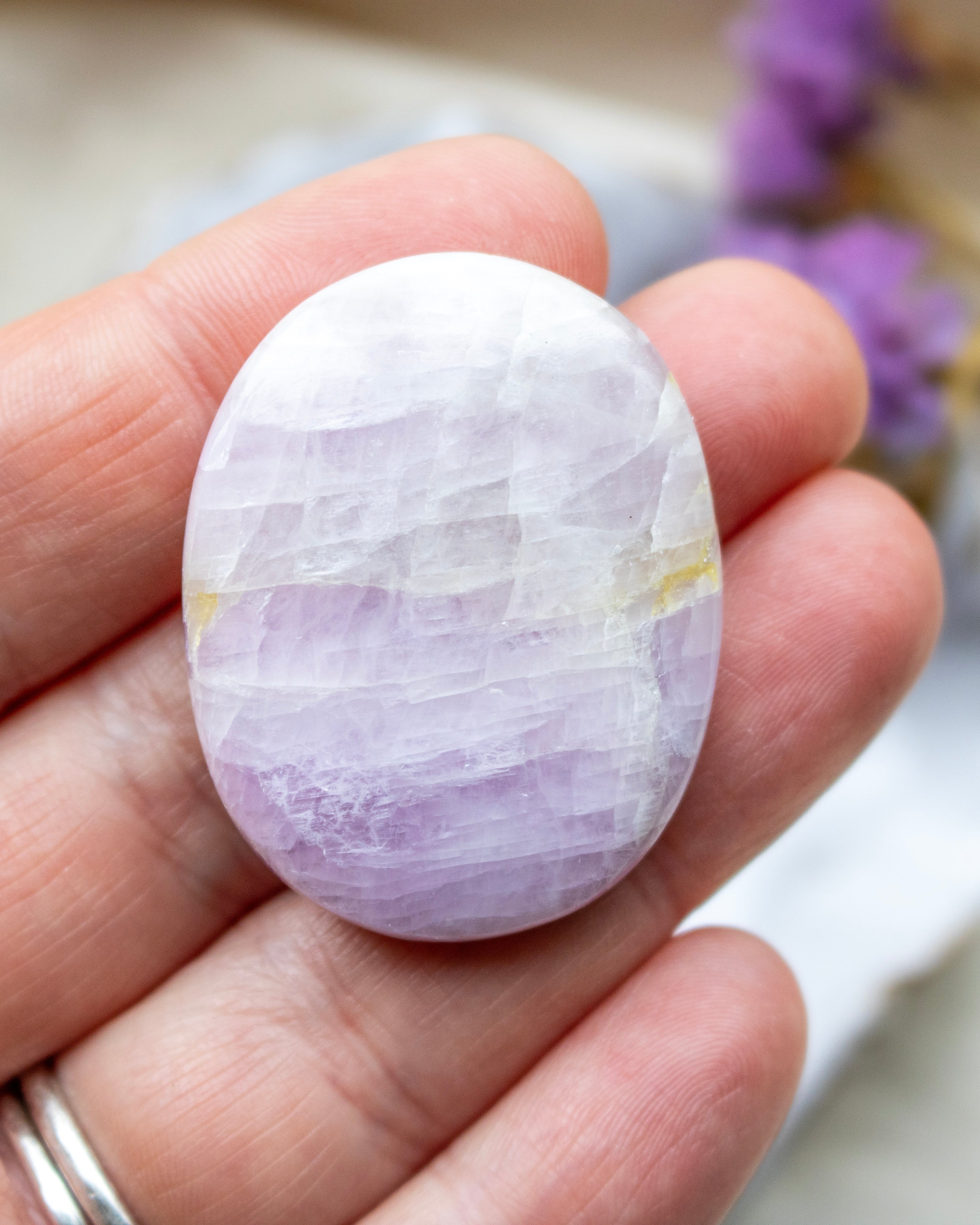 Hand holding a purple and white stone with a blurred background