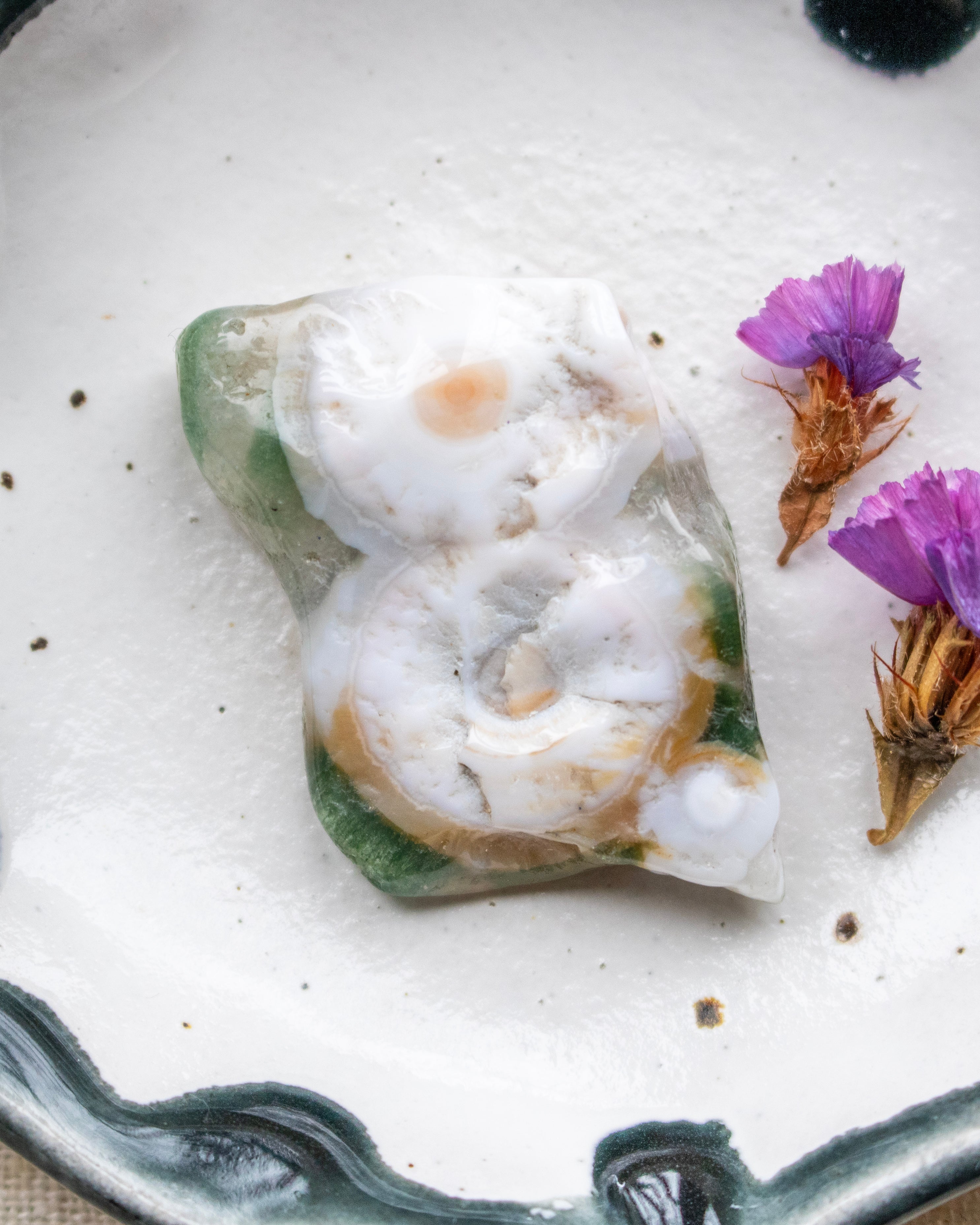 Decorative stone on a white plate with purple flowers