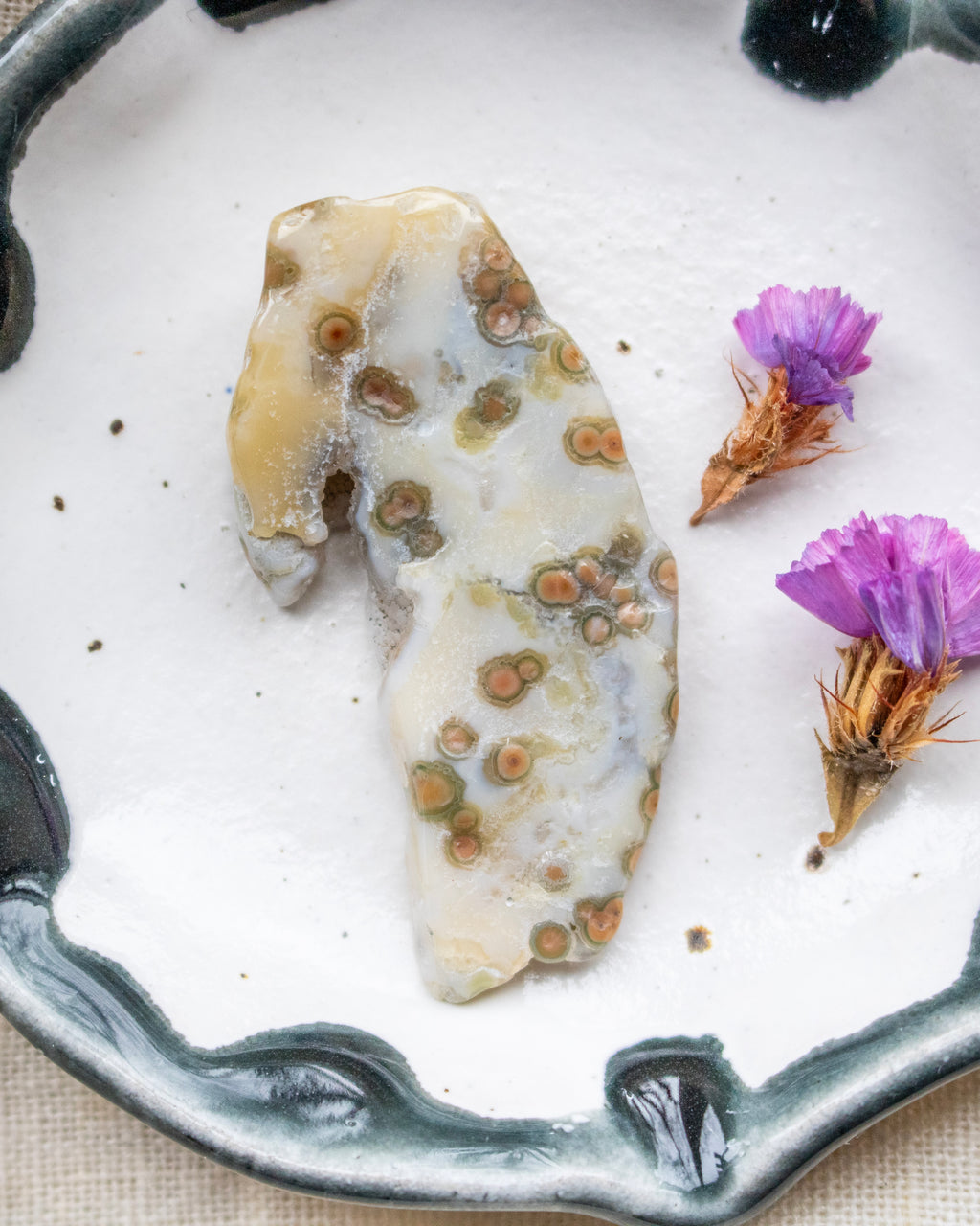 Decorative stone with natural patterns on a white plate with purple flowers