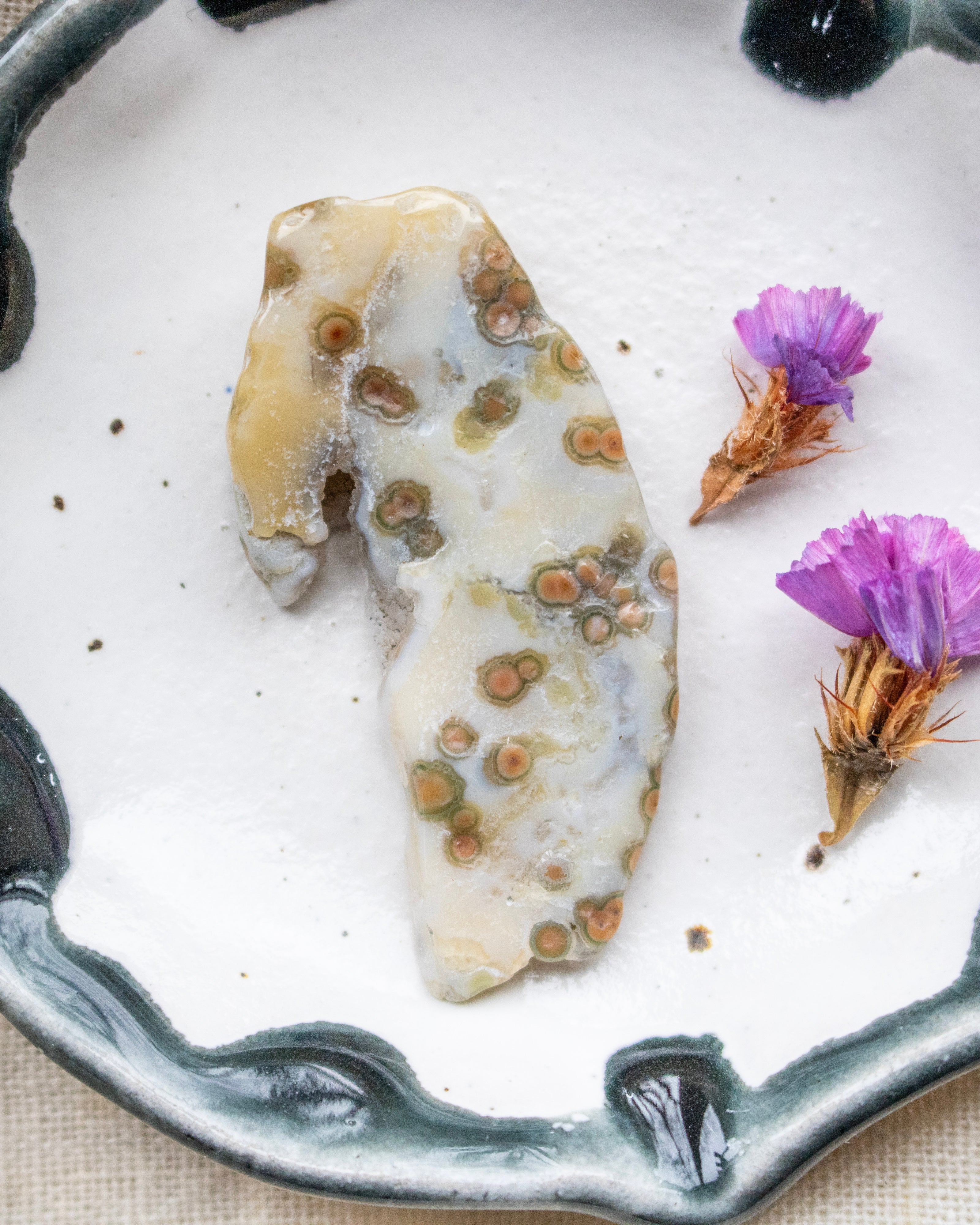Decorative stone with natural patterns on a white plate with purple flowers
