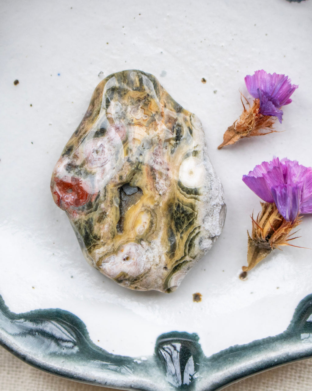 a patterned stone with purple flowers on a white background