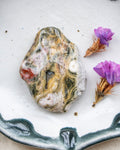a patterned stone with purple flowers on a white background