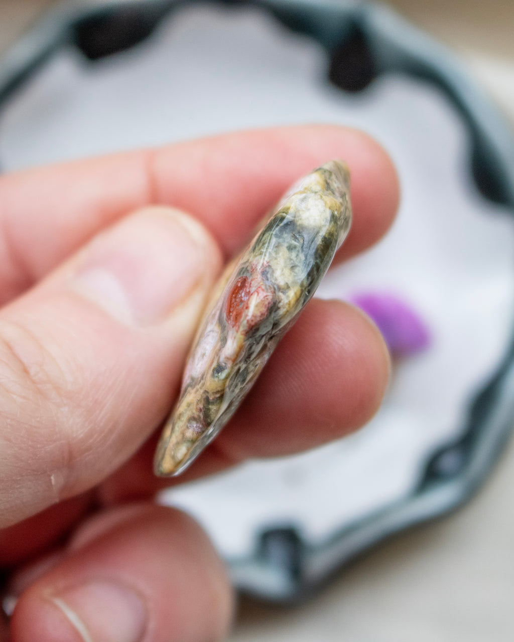 Hand holding a small, irregularly shaped stone with a blurred background
