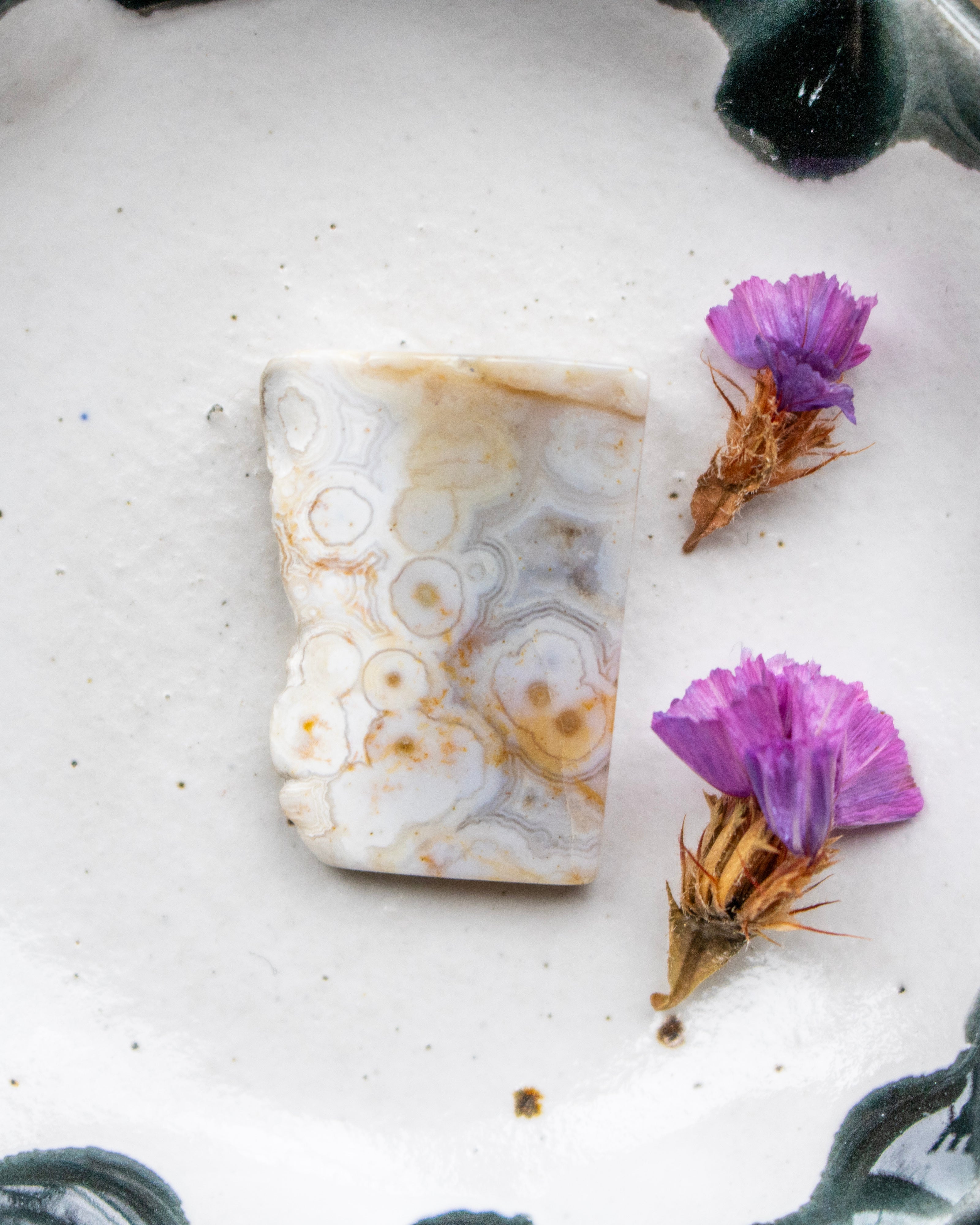 Marbled stone with purple flowers on a textured surface