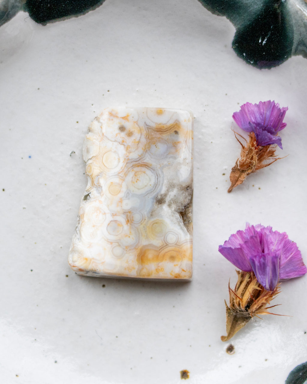 Marble-like stone with purple flowers on a white surface