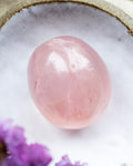 Pink crystal ball on a textured white surface with purple flowers.
