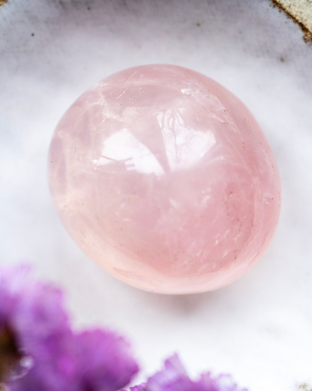 Pink stone on a white surface with purple watercolor effect