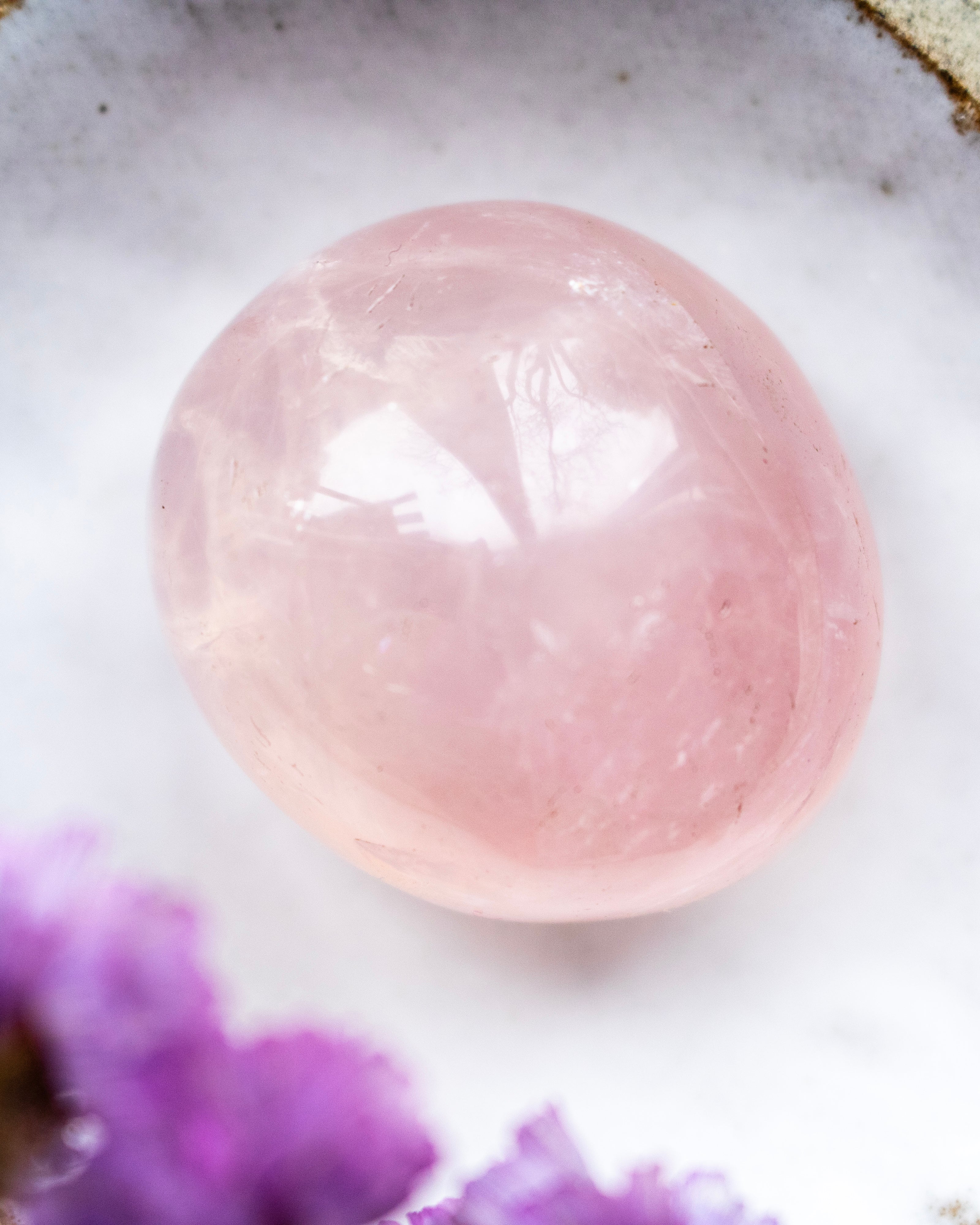 Pink stone on a white surface with purple watercolor effect