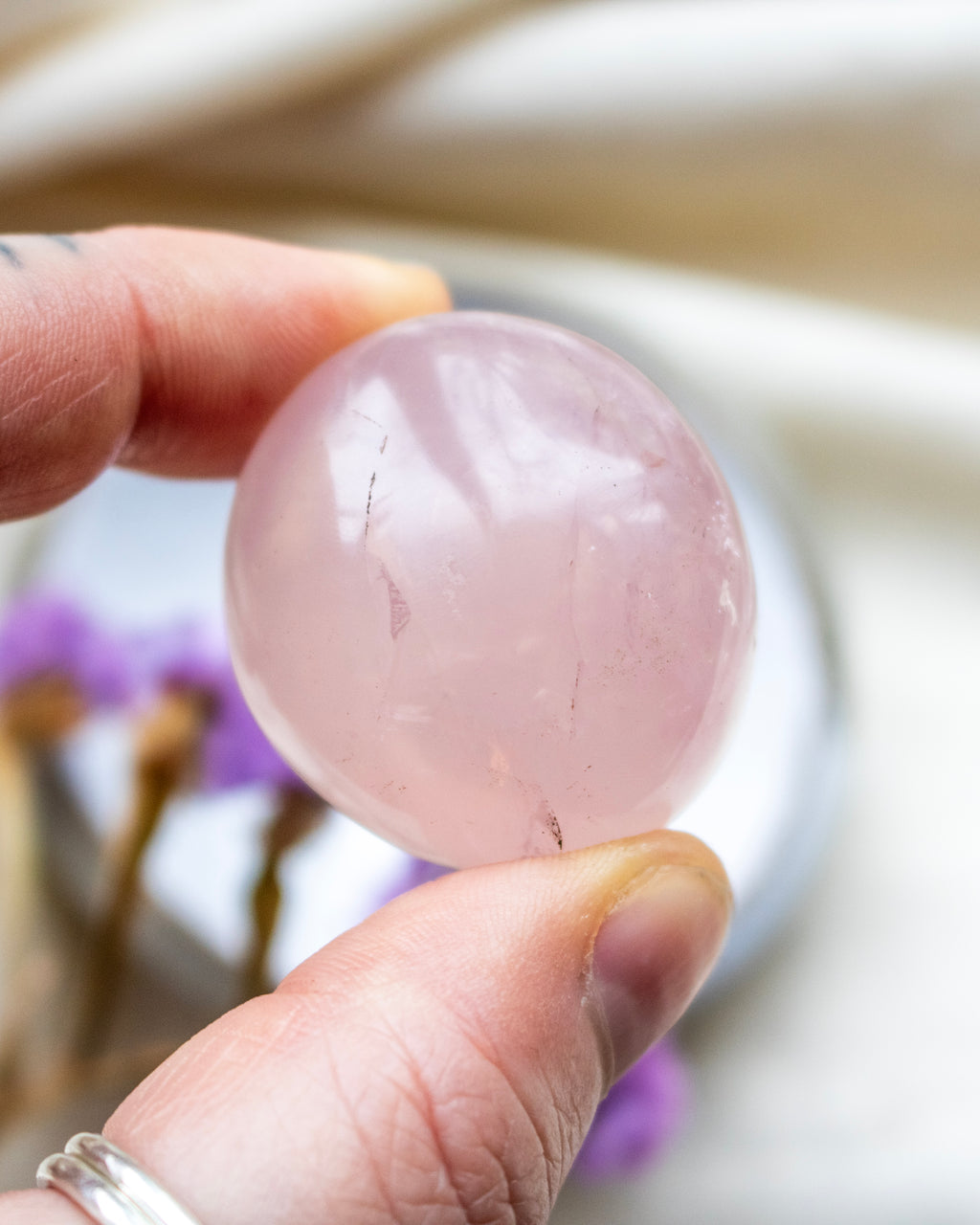Hand holding a pink crystal ball with blurred background