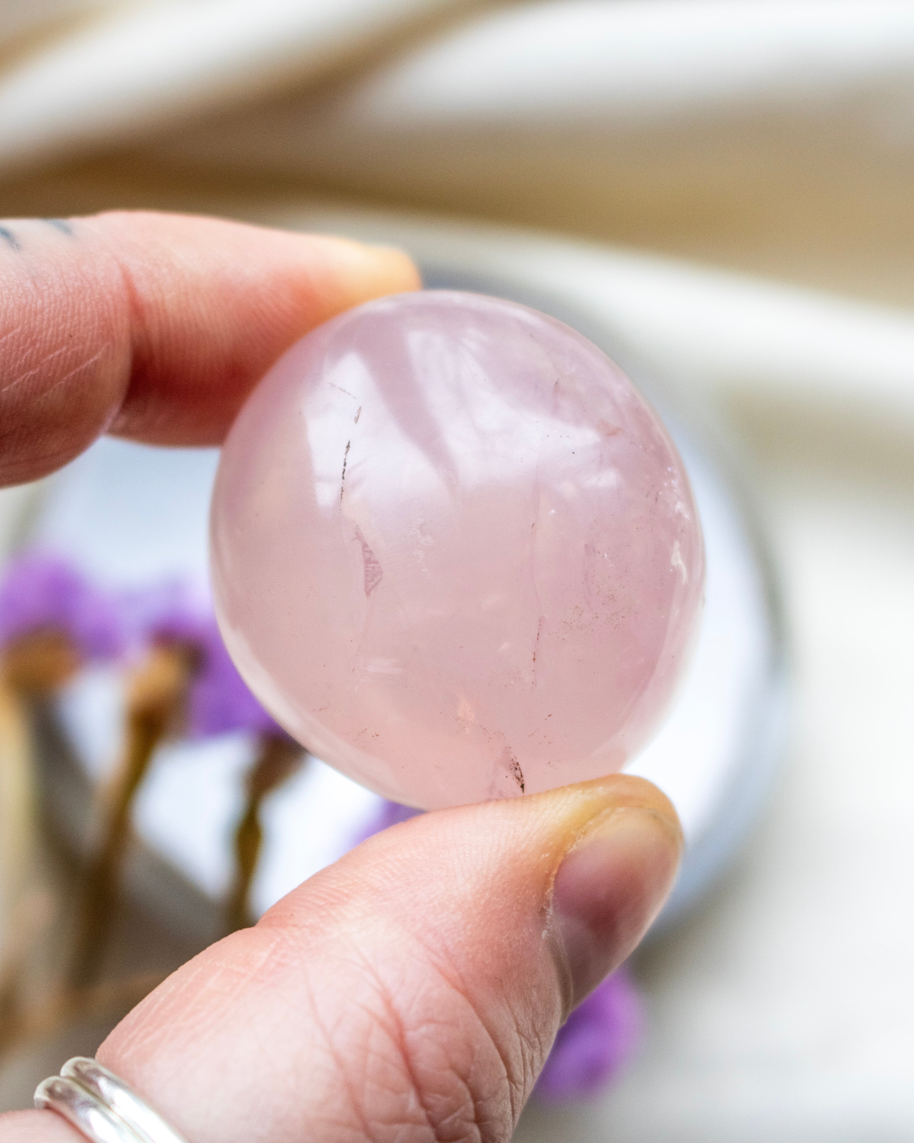 Hand holding a pink crystal ball with blurred background