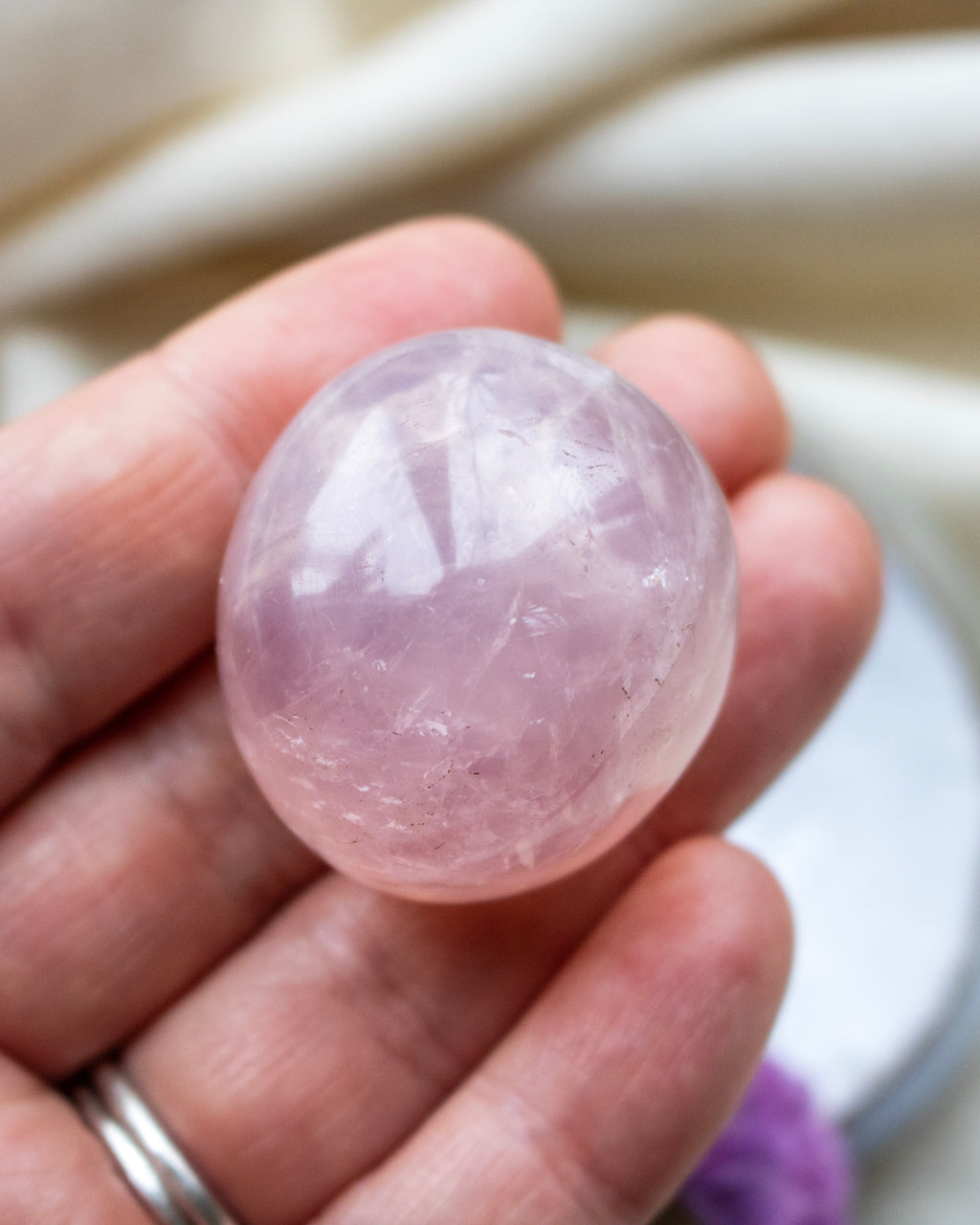 Pink crystal ball held in a hand with a blurred background