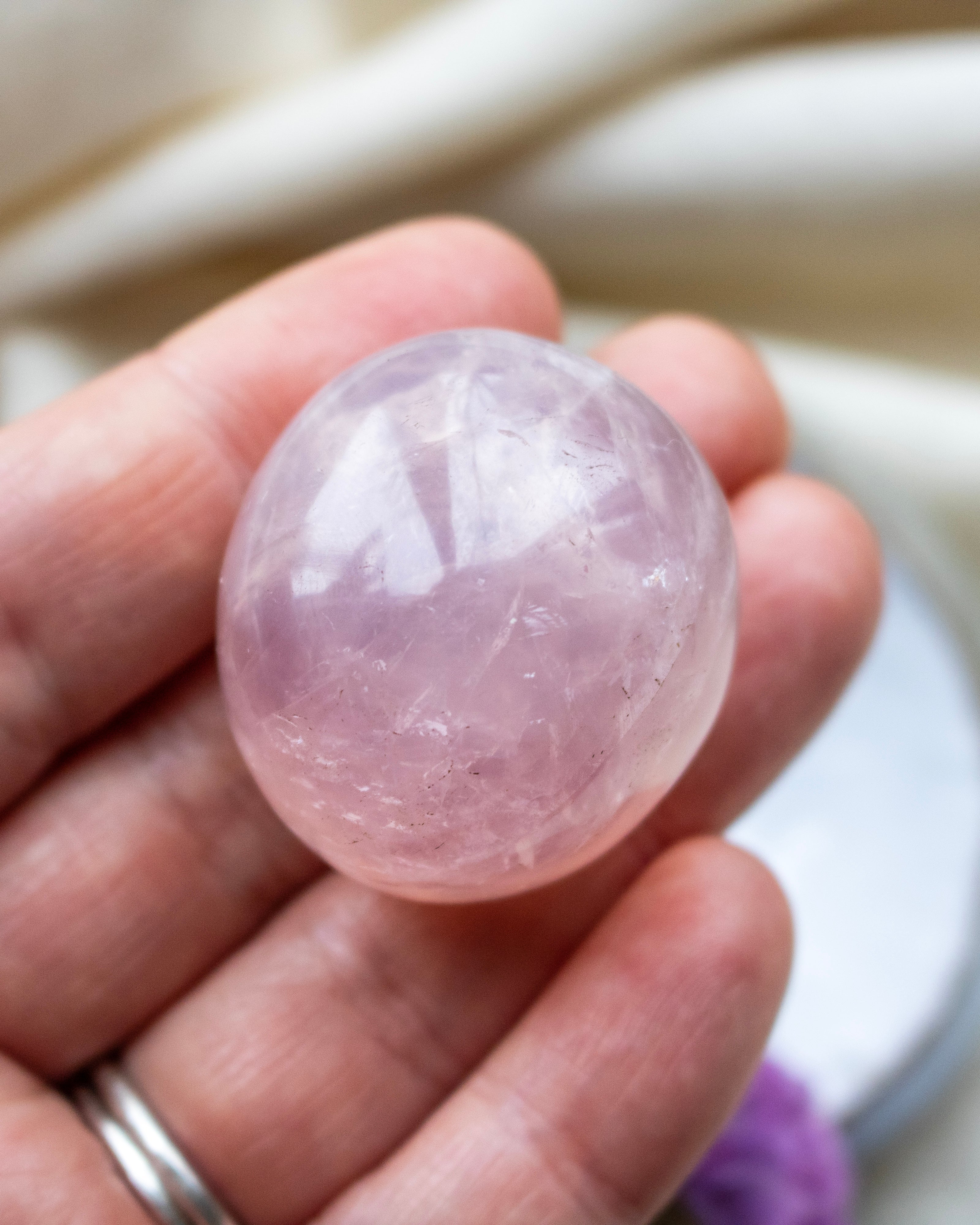 Pink crystal ball held in a hand with a blurred background