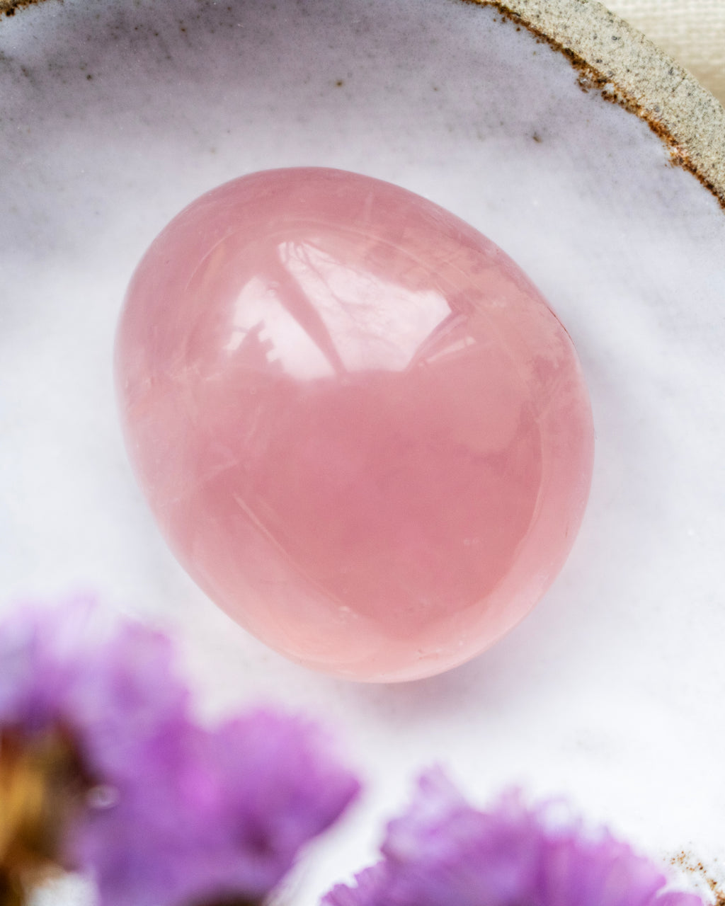 Pink stone on a white background with purple flowers