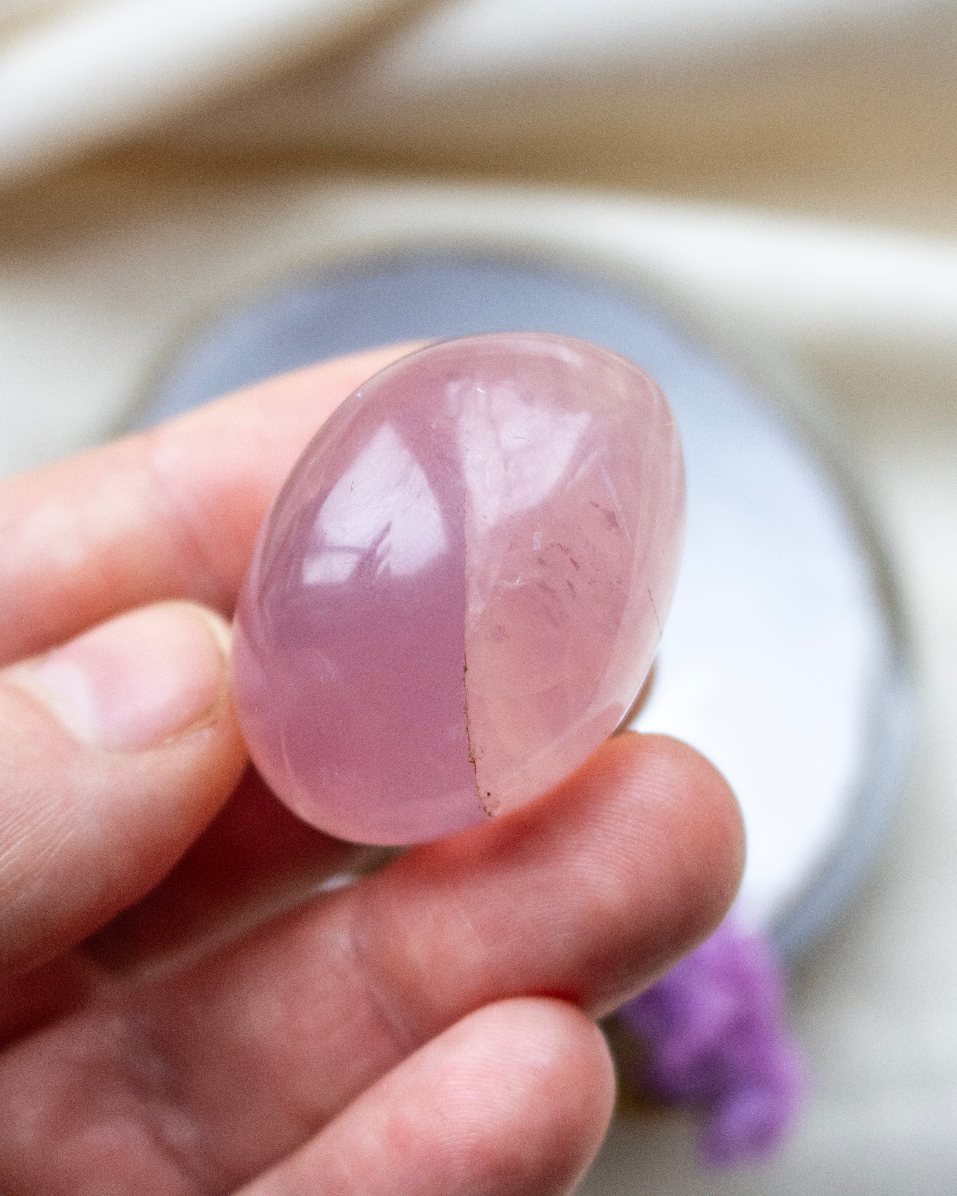 Hand holding a pink crystal stone with a blurred background