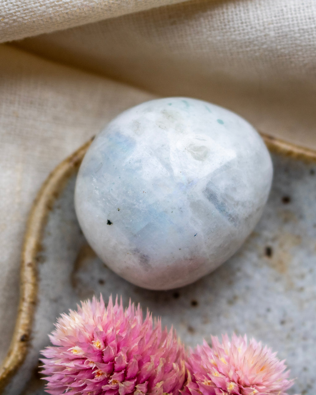 White marble sphere on a textured surface with pink flowers