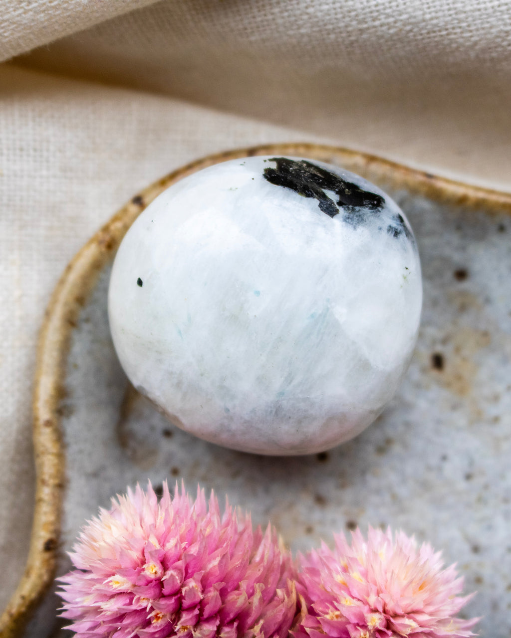 Marble sphere on a textured surface with pink flowers