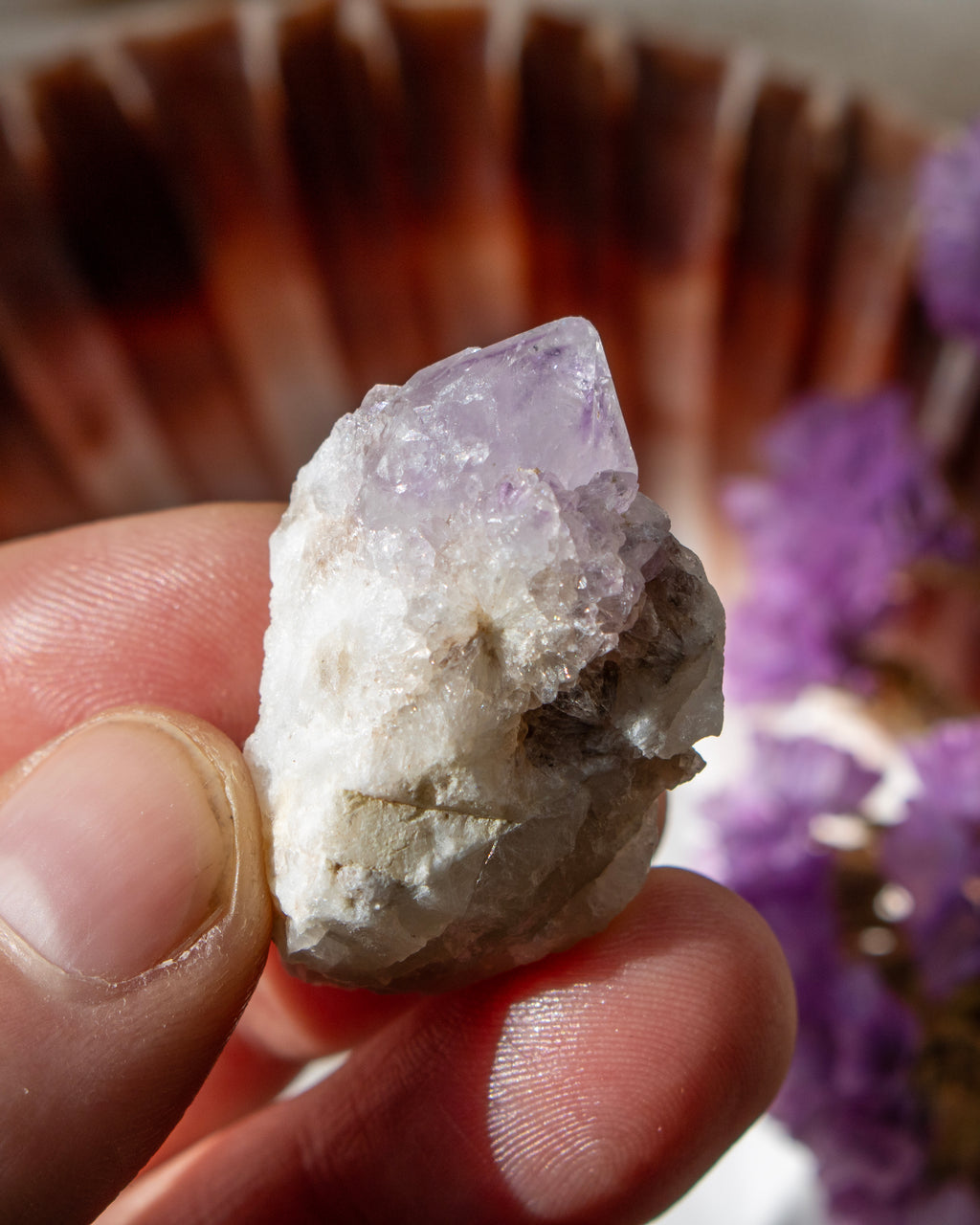 Hand holding a crystal rock with a blurred background