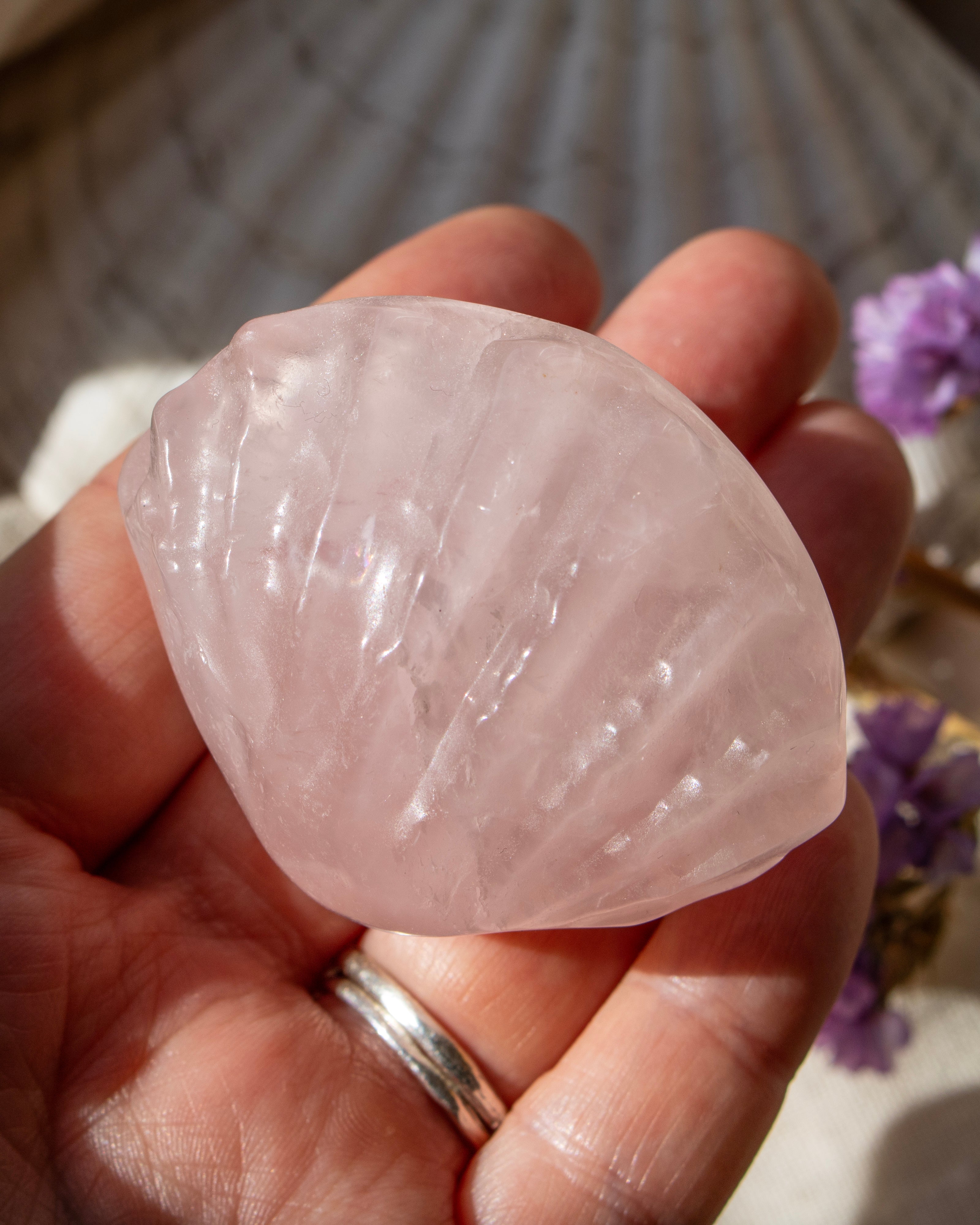 Hand holding a pink crystal with blurred background