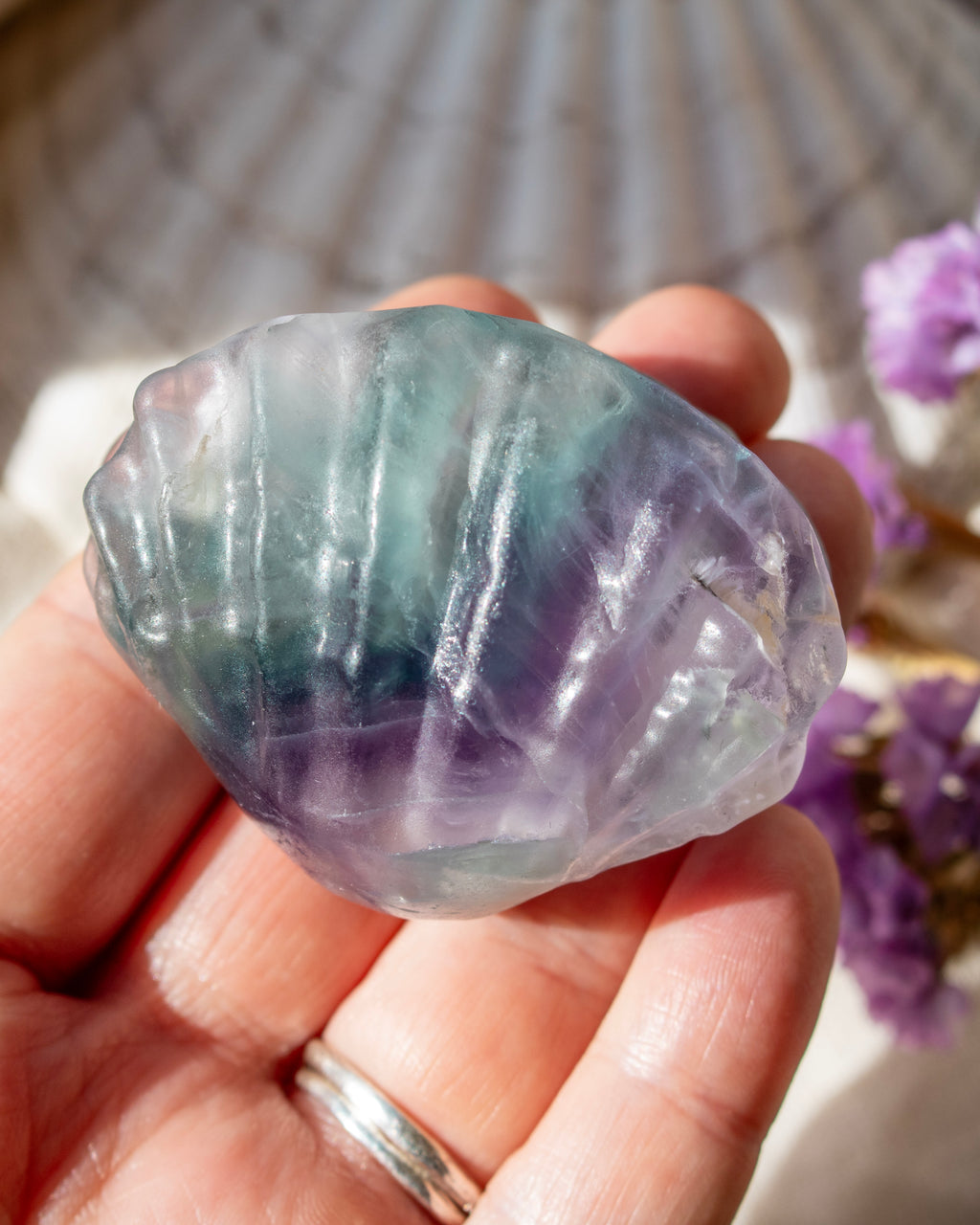 Hand holding a fluorite crystal with a blurred background