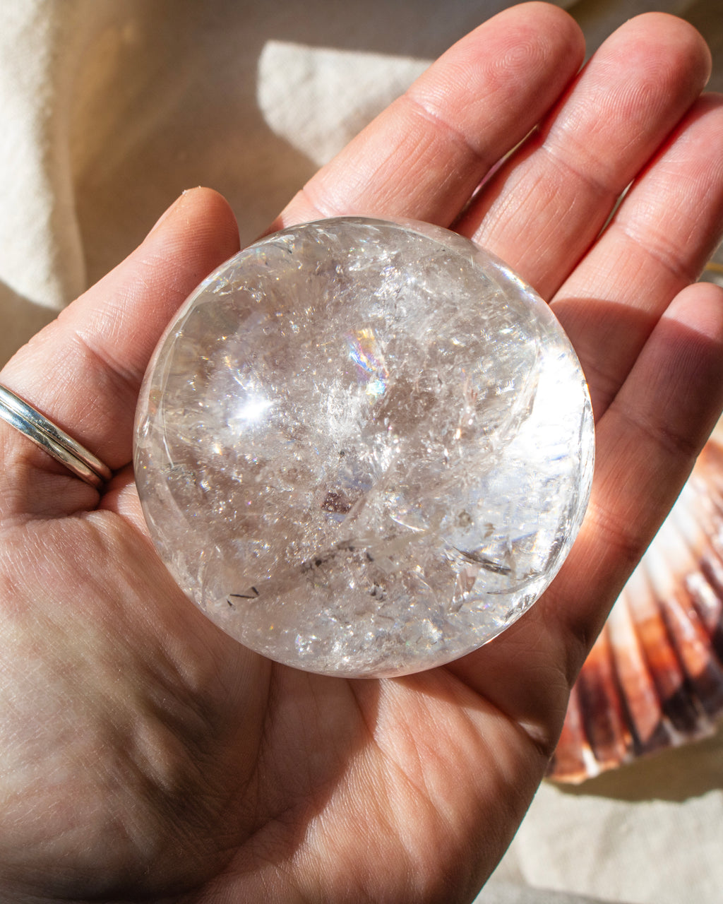 Hand holding a clear crystal ball with sunlight casting shadows
