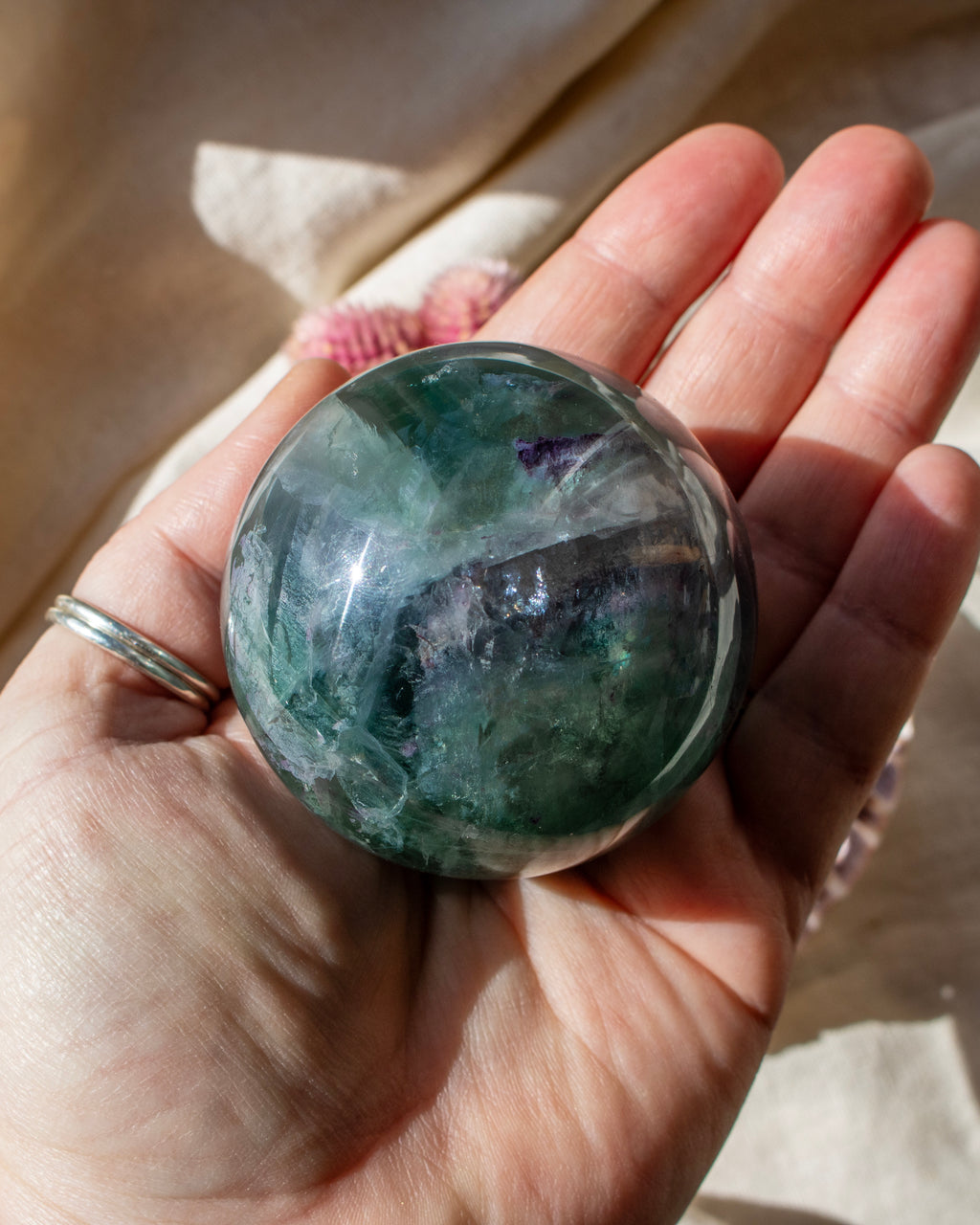Hand holding a green crystal ball with a blurred background