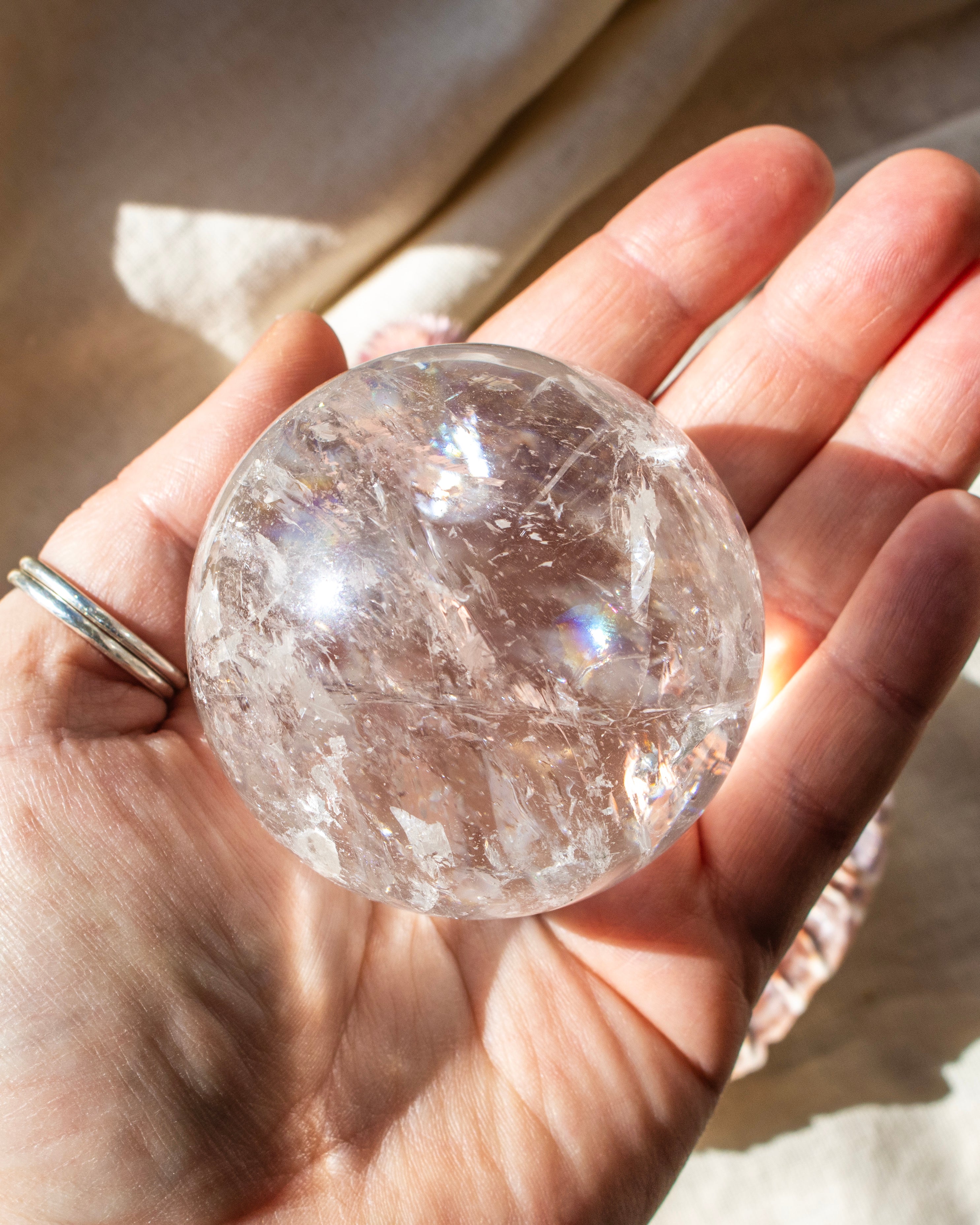 Clear crystal sphere held in a hand with a blurred background