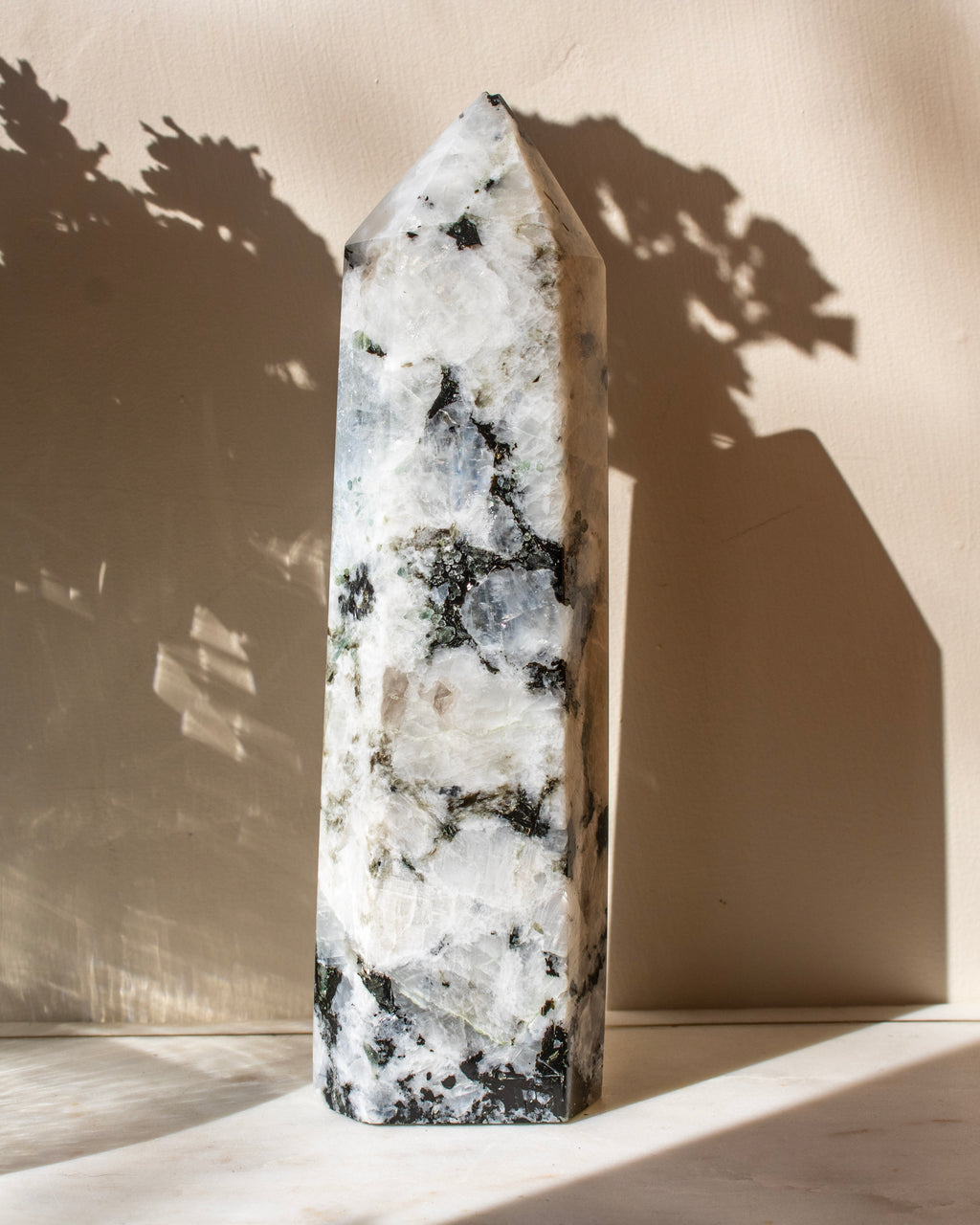 Marbled obelisk on a beige surface with soft shadows