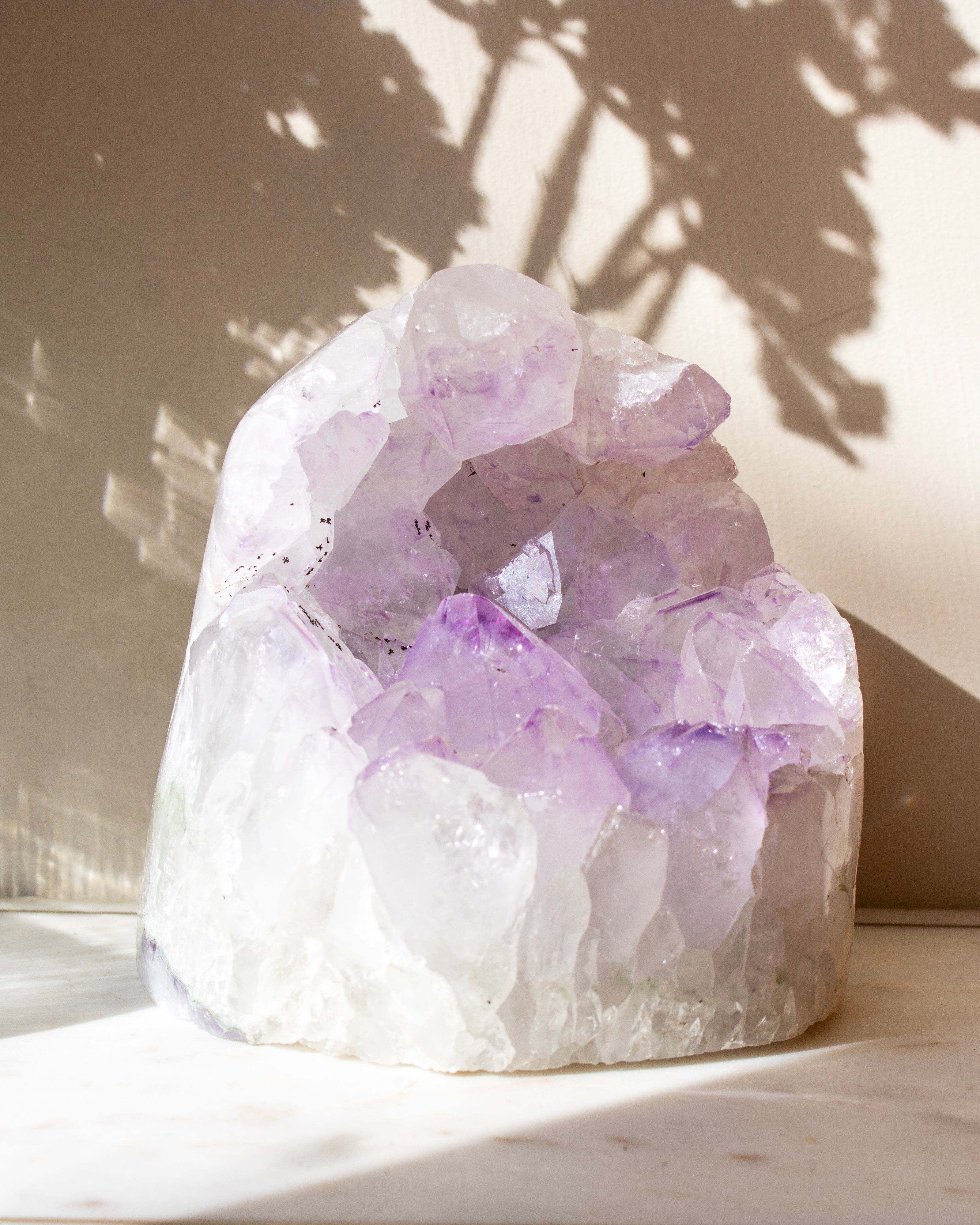 a pale purple crystal cluster against a beige background