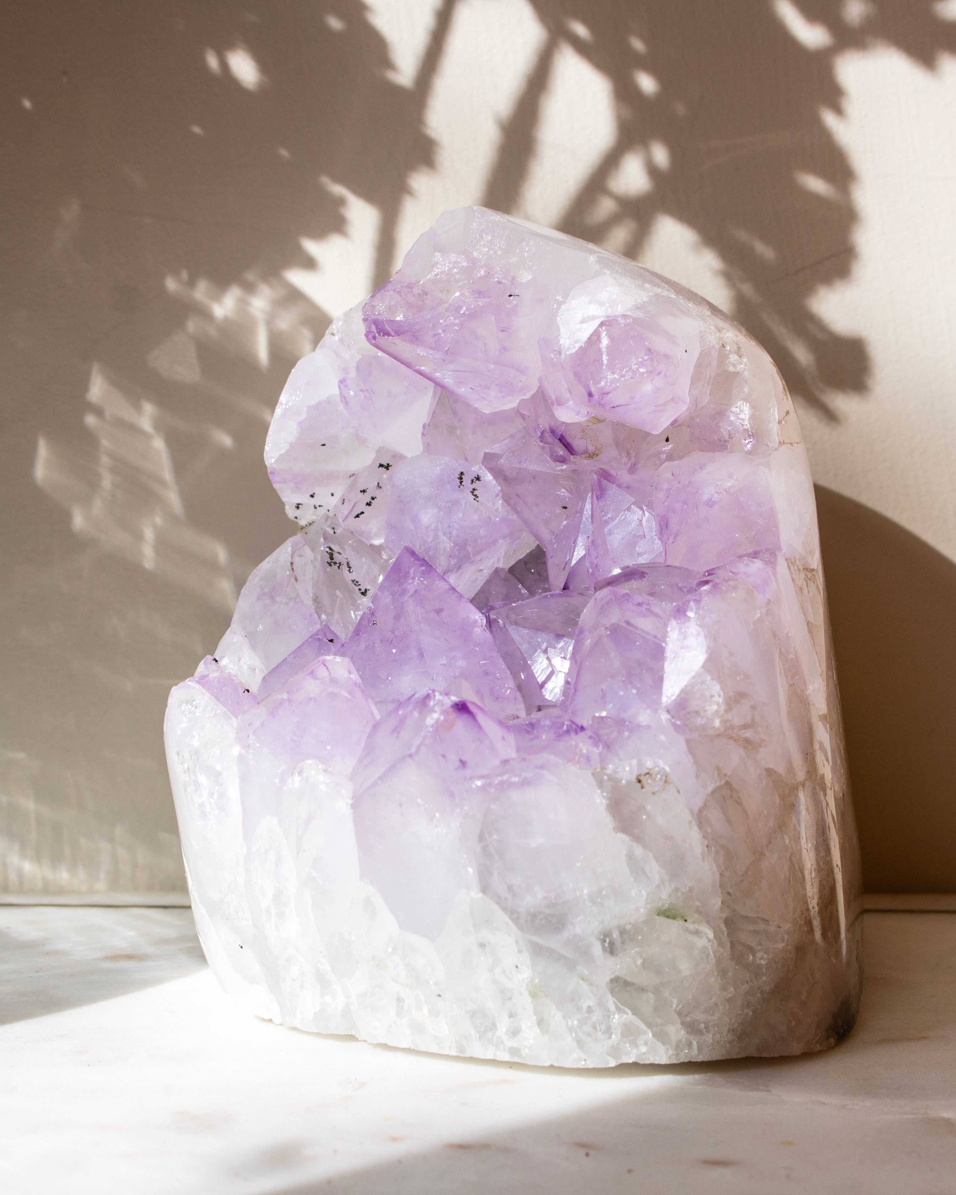 a pale purple crystal cluster against a beige background