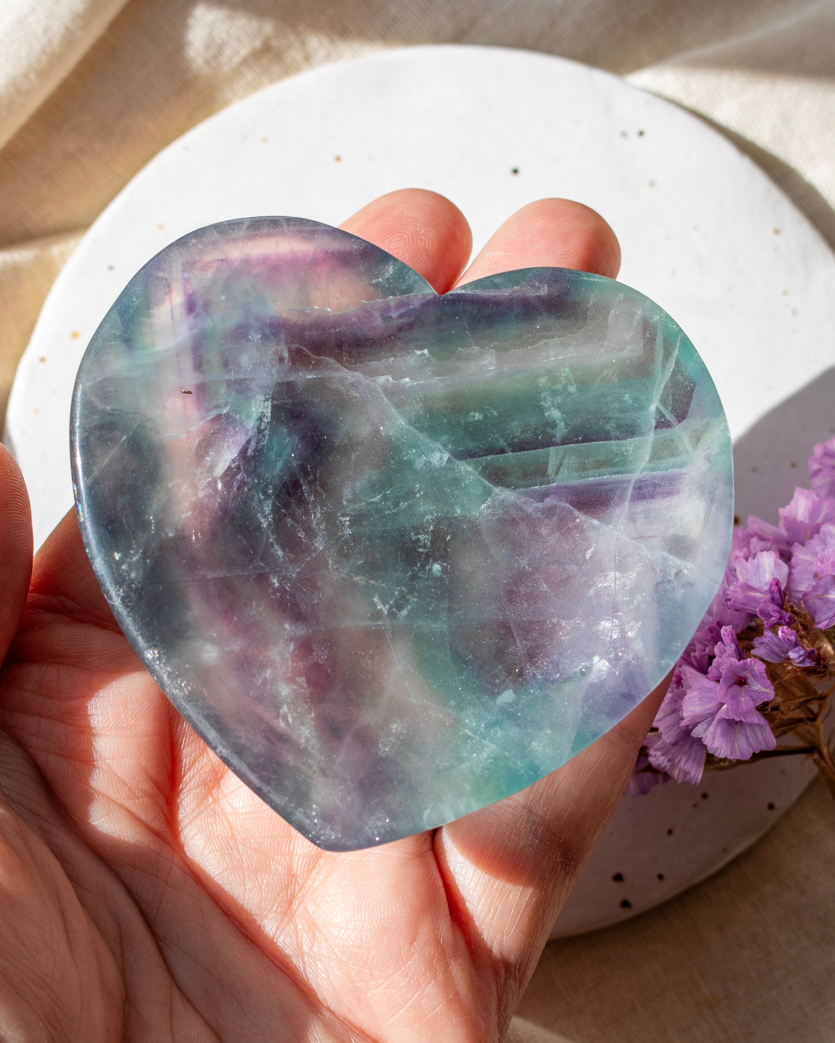 Heart-shaped crystal held in a hand with a blurred background