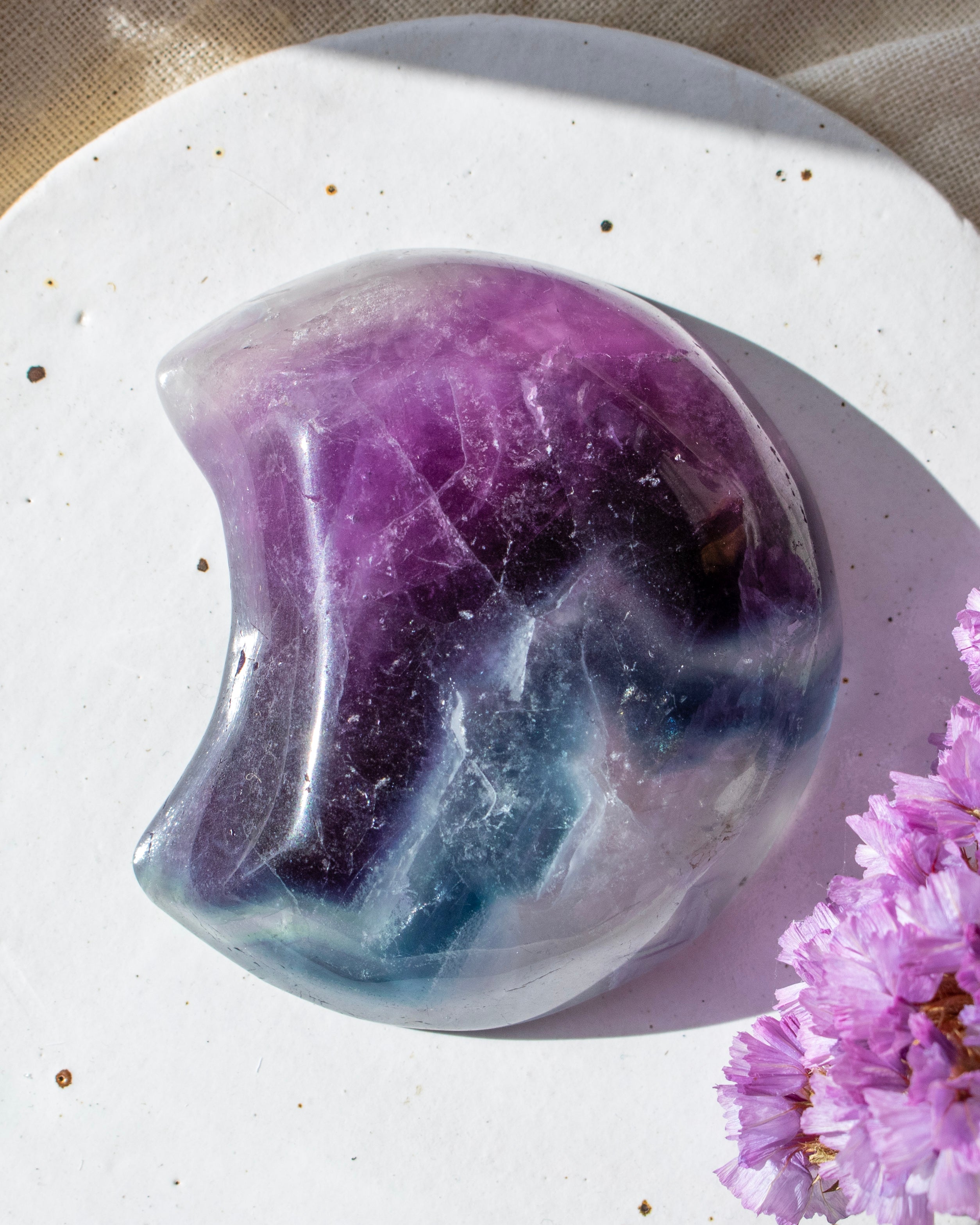 Crystal with purple and white colors on a light background with pink flowers