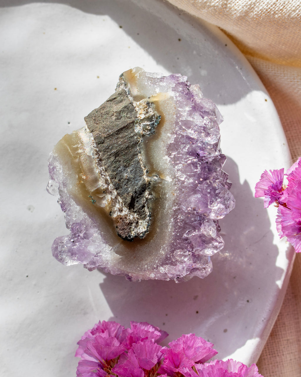 Crystal rock on a white plate with pink flowers