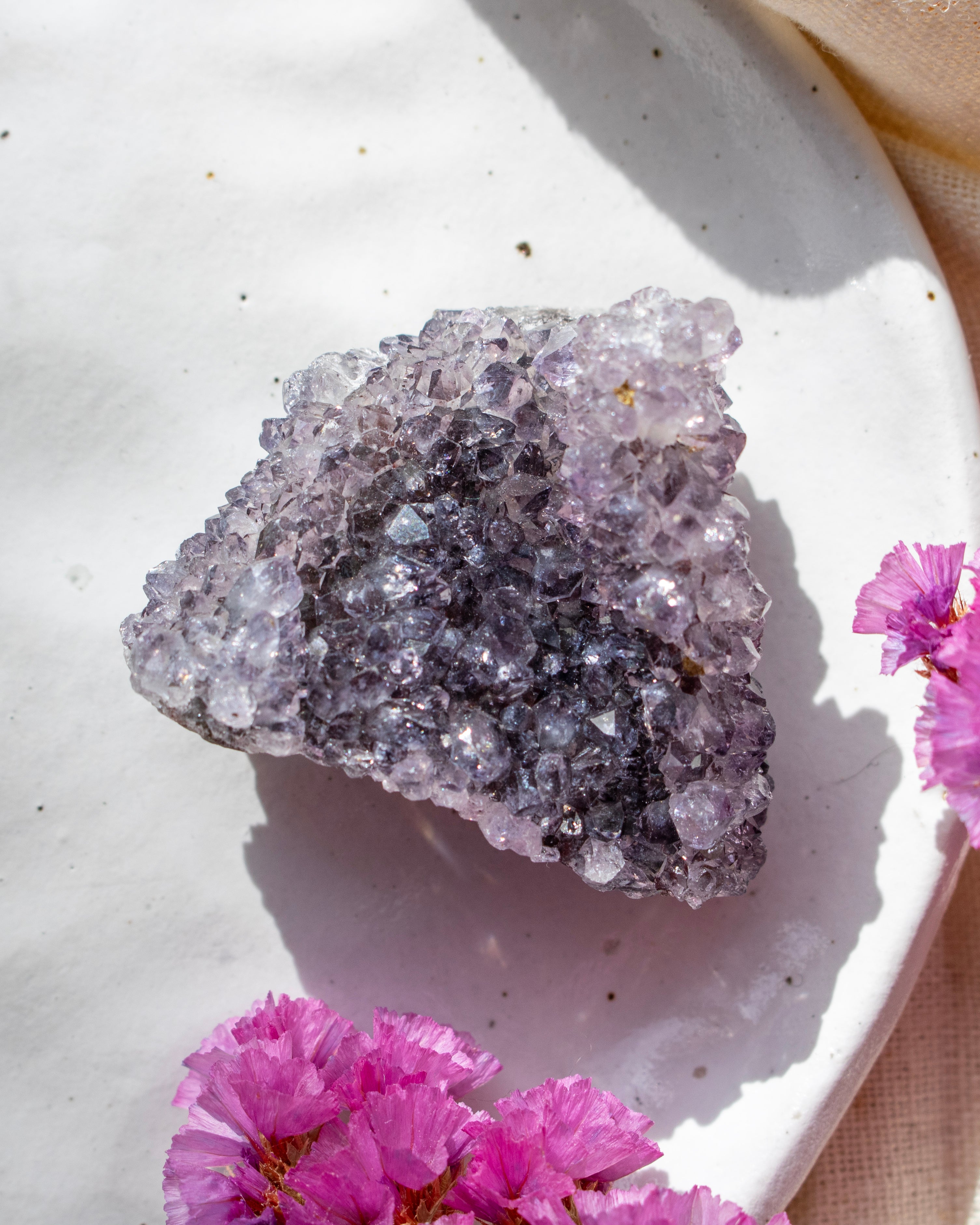 Amethyst crystal on a white plate with pink flowers