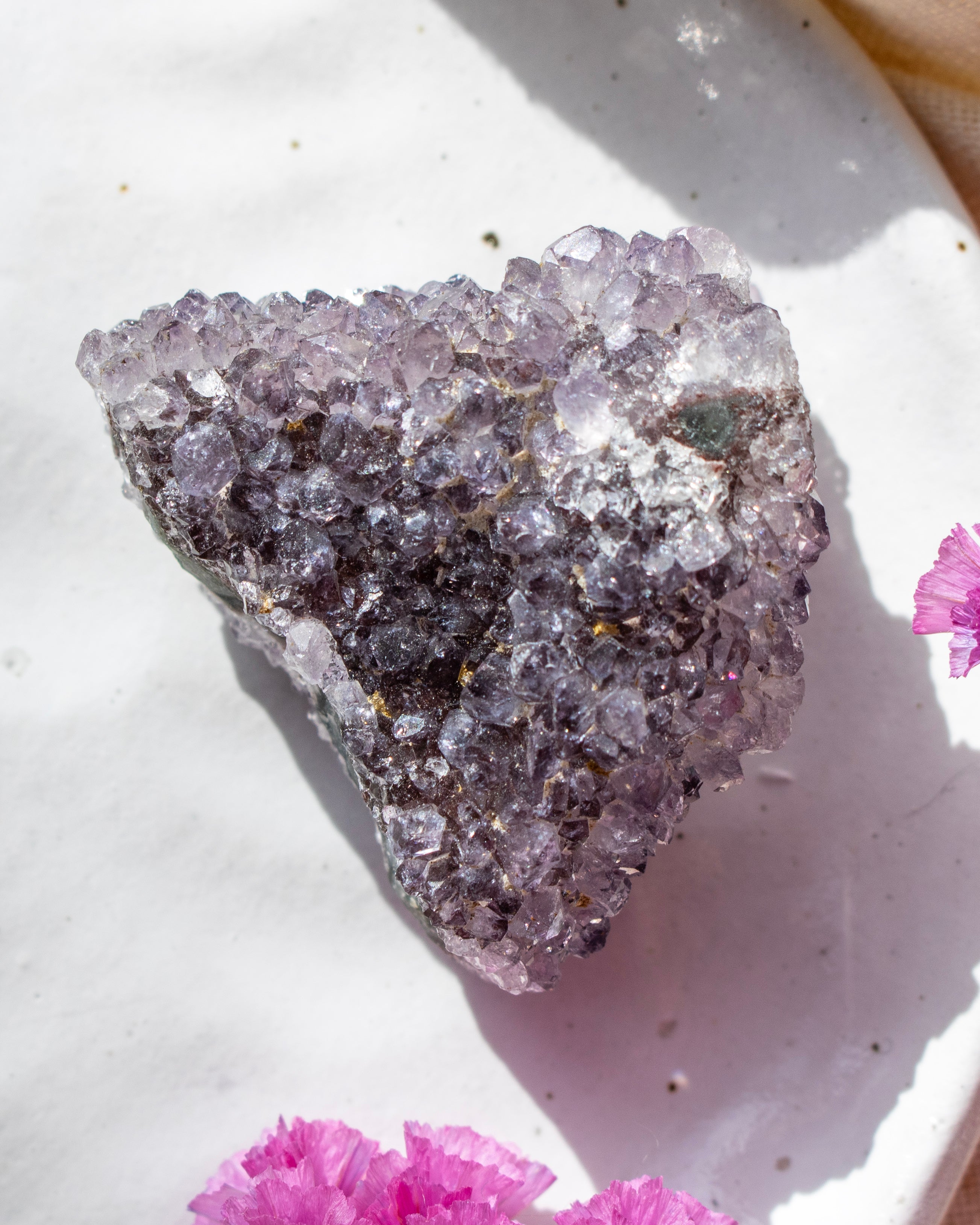 Crystal rock on a white surface with pink flowers