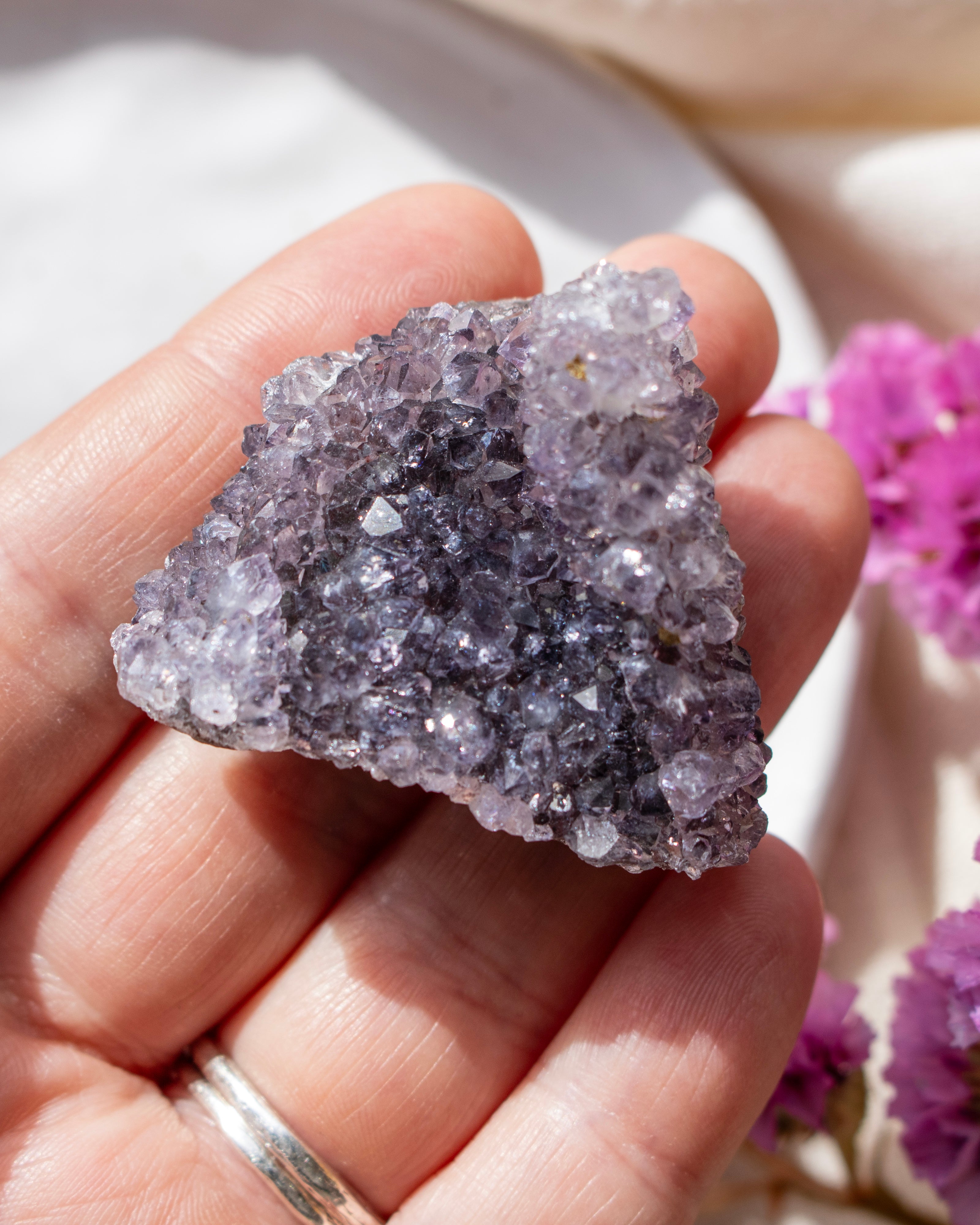 Hand holding a purple crystal with a blurred background