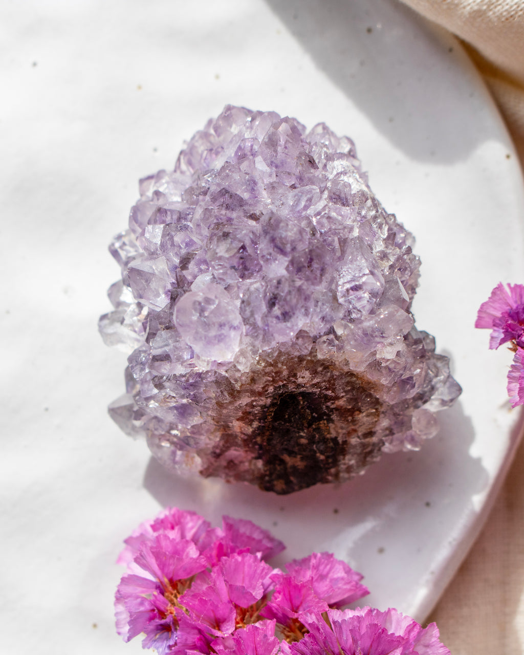 Amethyst crystal on a white plate with pink flowers